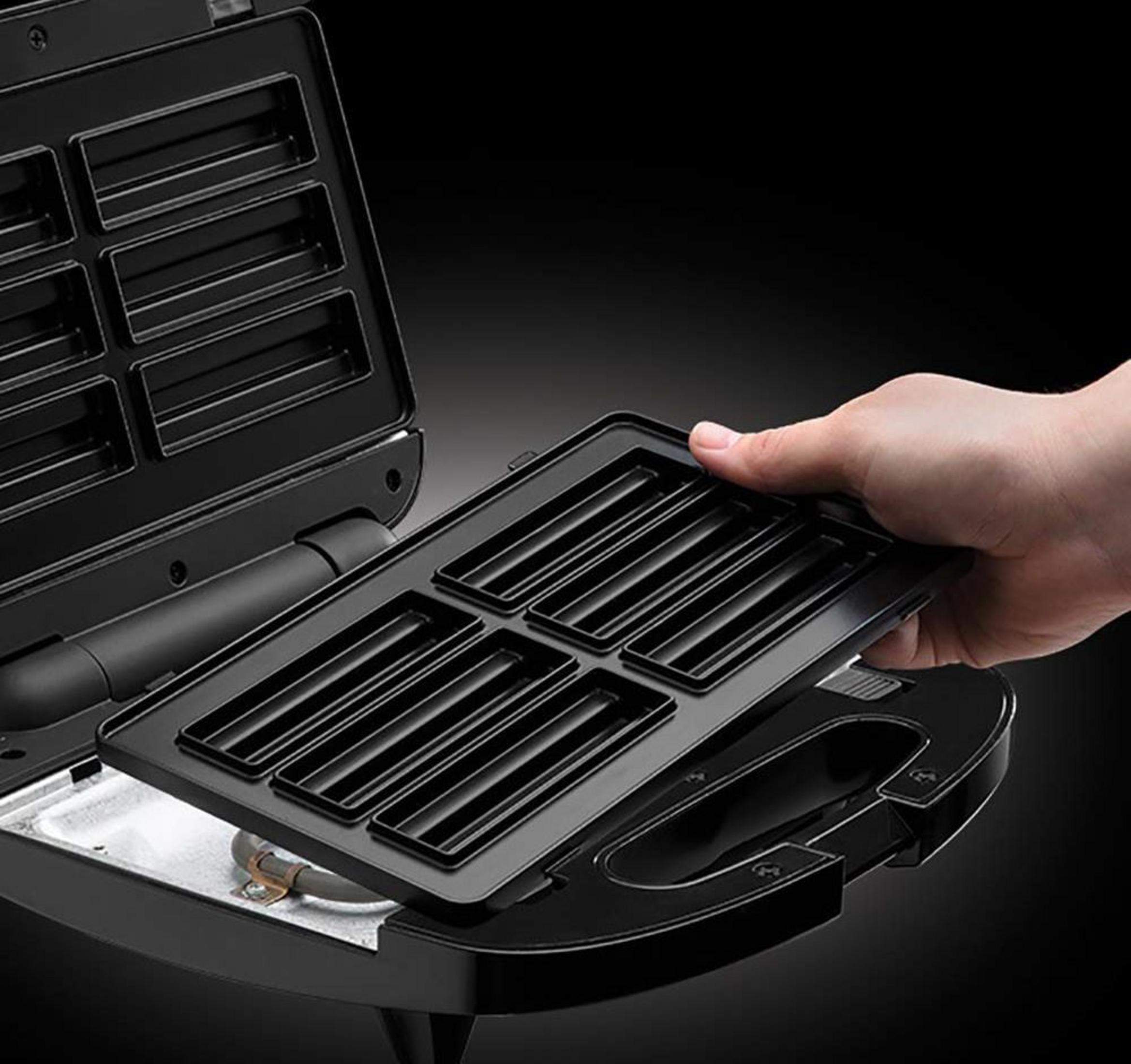 Una mano inserisce una teglia rettangolare in una piastra per panini nera.