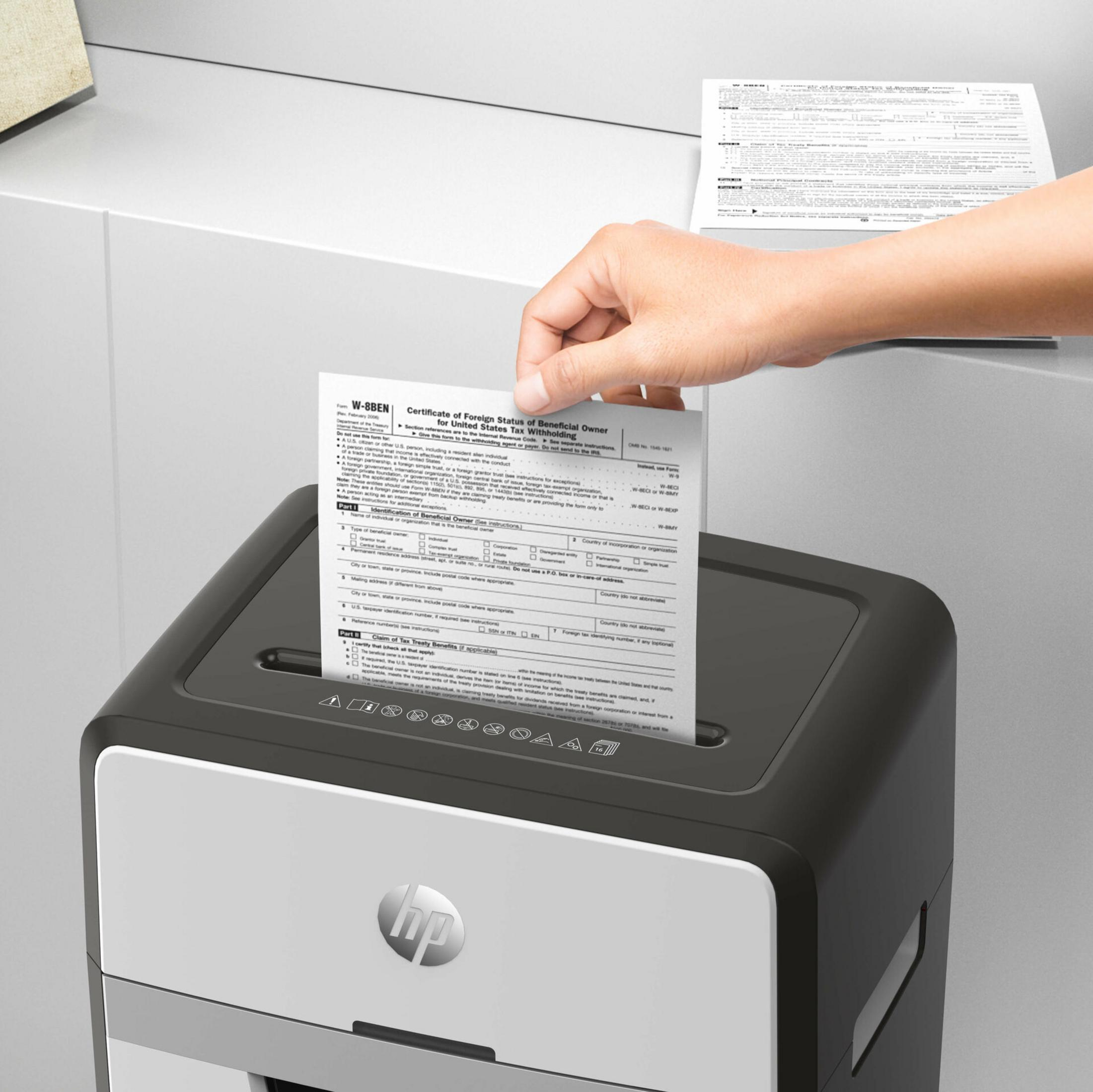 Una mano inserisce un modulo in un distruggidocumenti.
