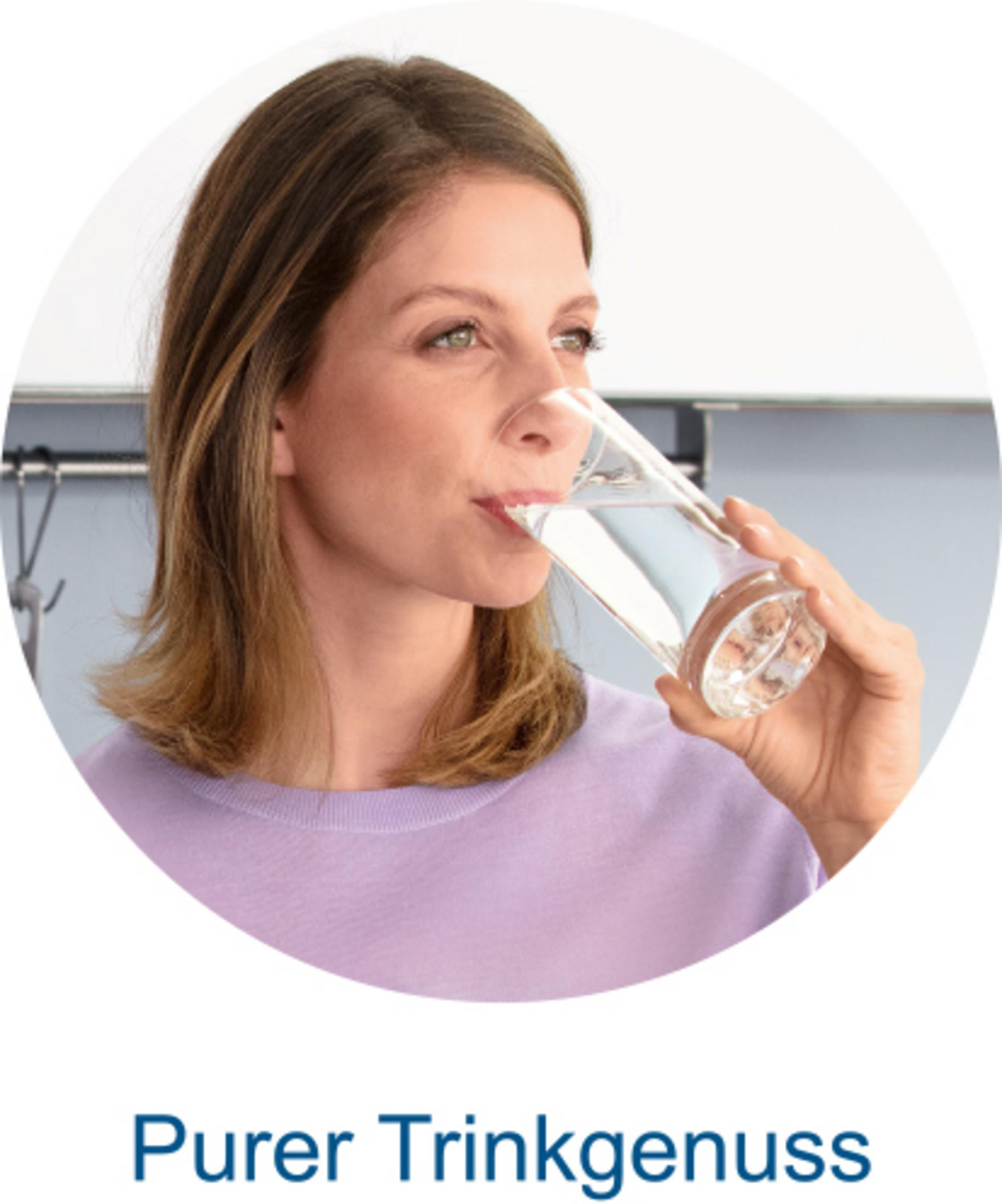 A woman drinks from a glass of water.