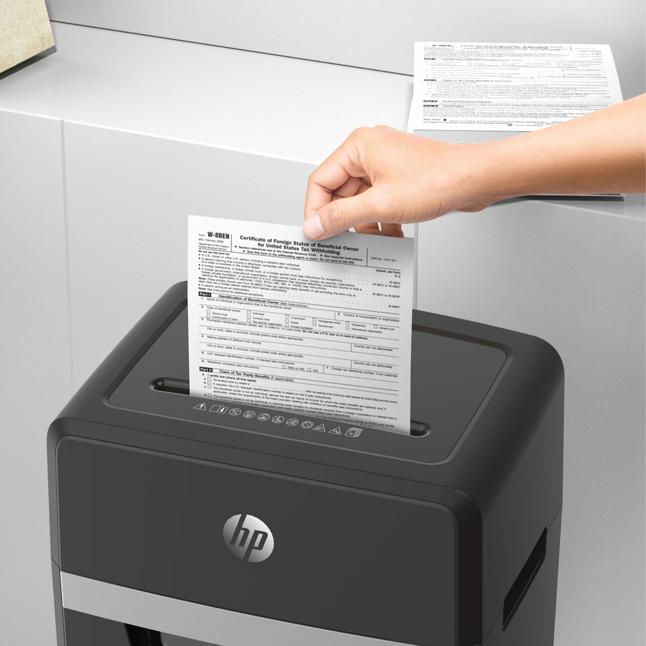 Una mano inserisce un modulo in un distruggidocumenti. Il distruggidocumenti ha il logo HP.