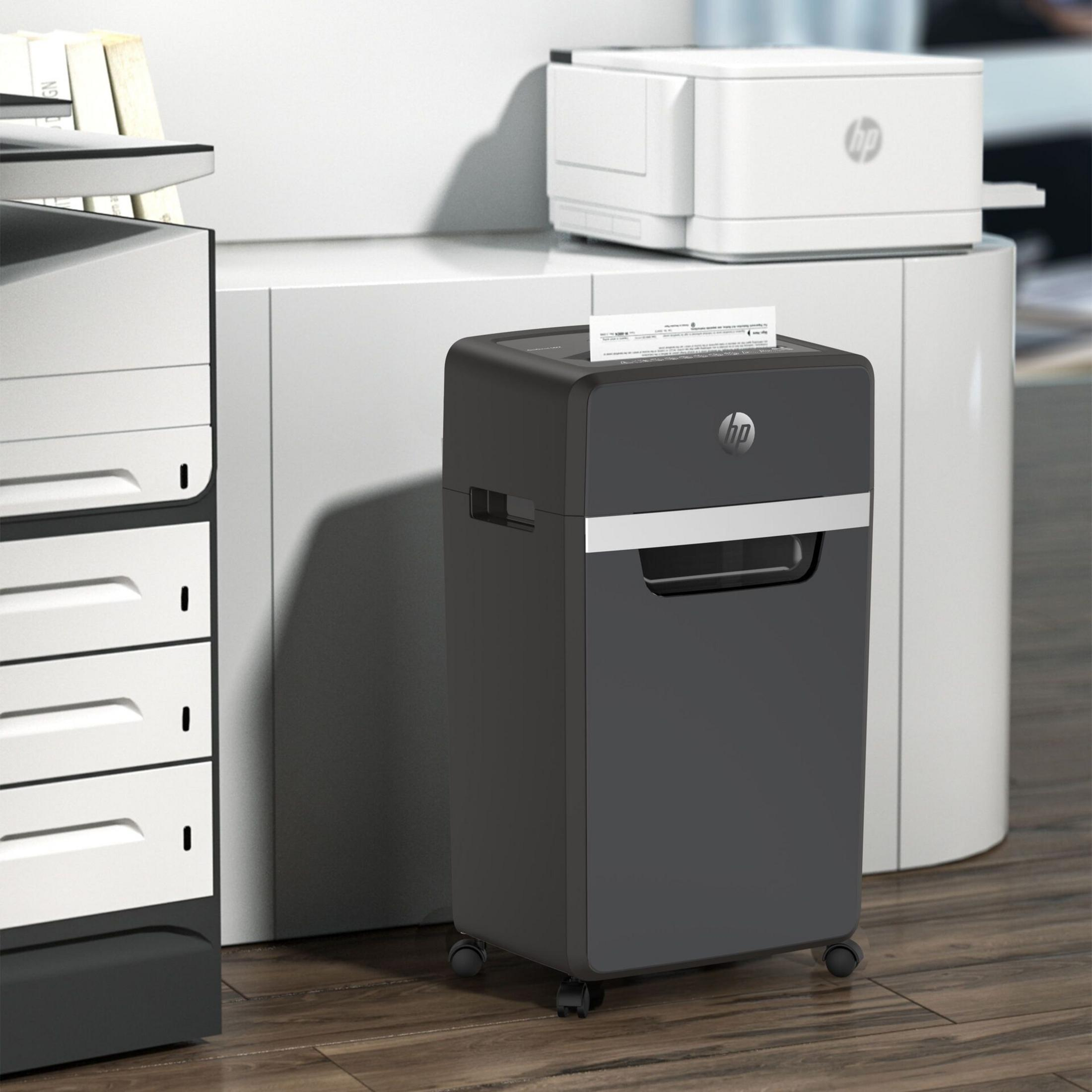 Un distruggi documenti HP scuro è davanti a una stampante bianca.