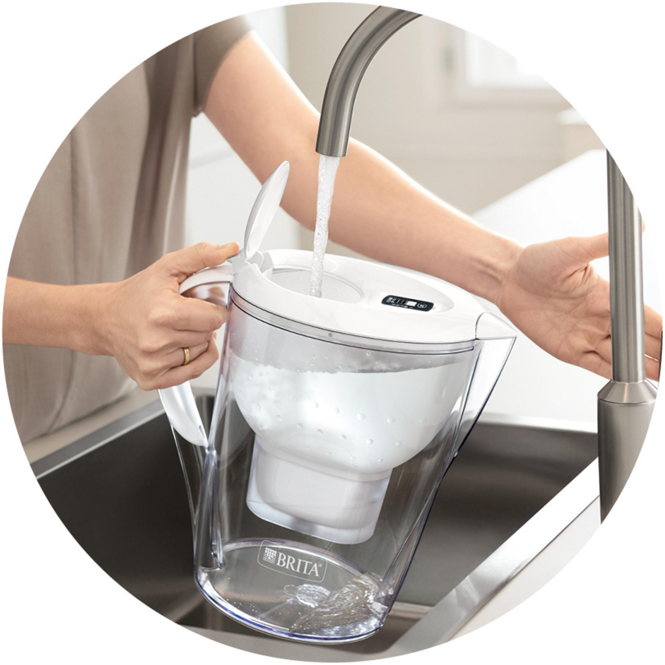 Eine Person füllt einen Brita-Wasserfilterkrug unter einem Wasserhahn in einer Spüle mit Wasser.