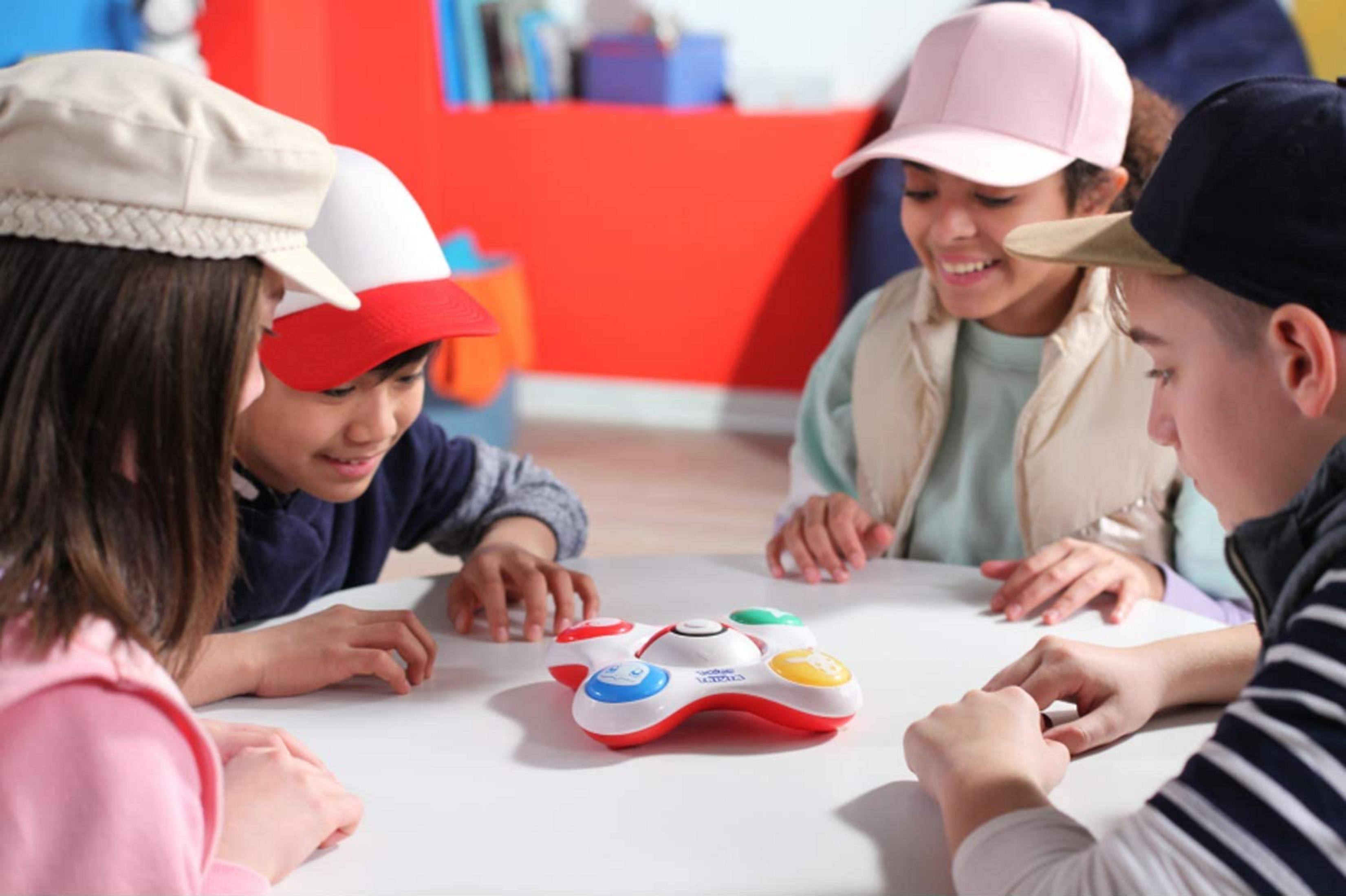 Vier Kinder spielen mit einem bunten Spielzeug auf einem Tisch.