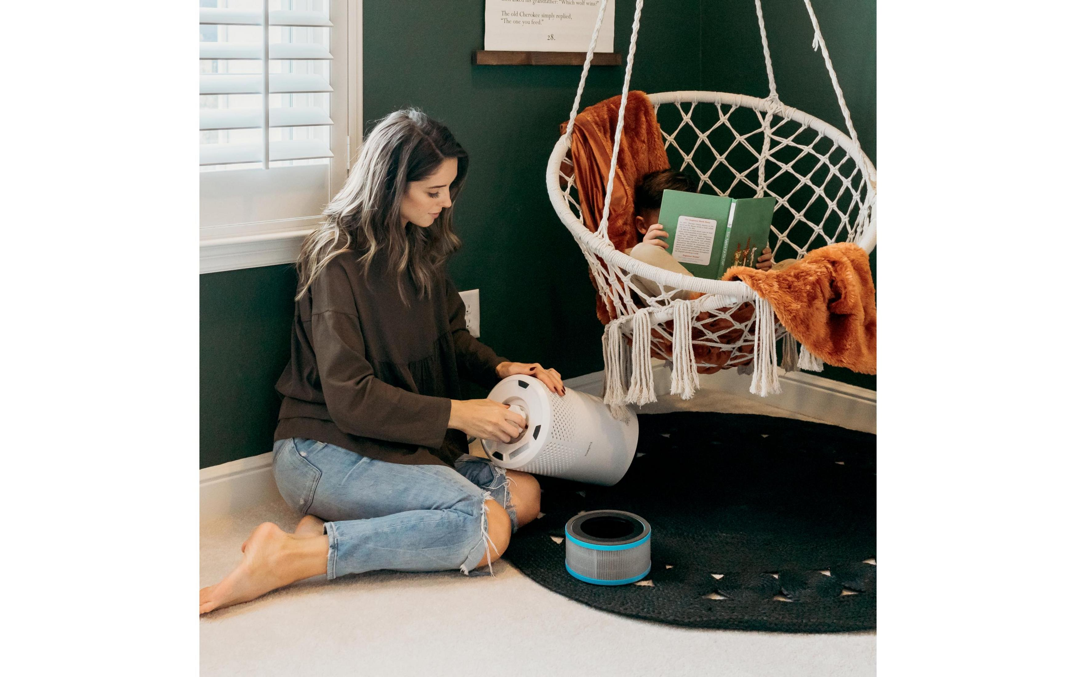 Kobieta wymienia filtr powietrza, podczas gdy dziecko czyta w wiszącym fotelu.