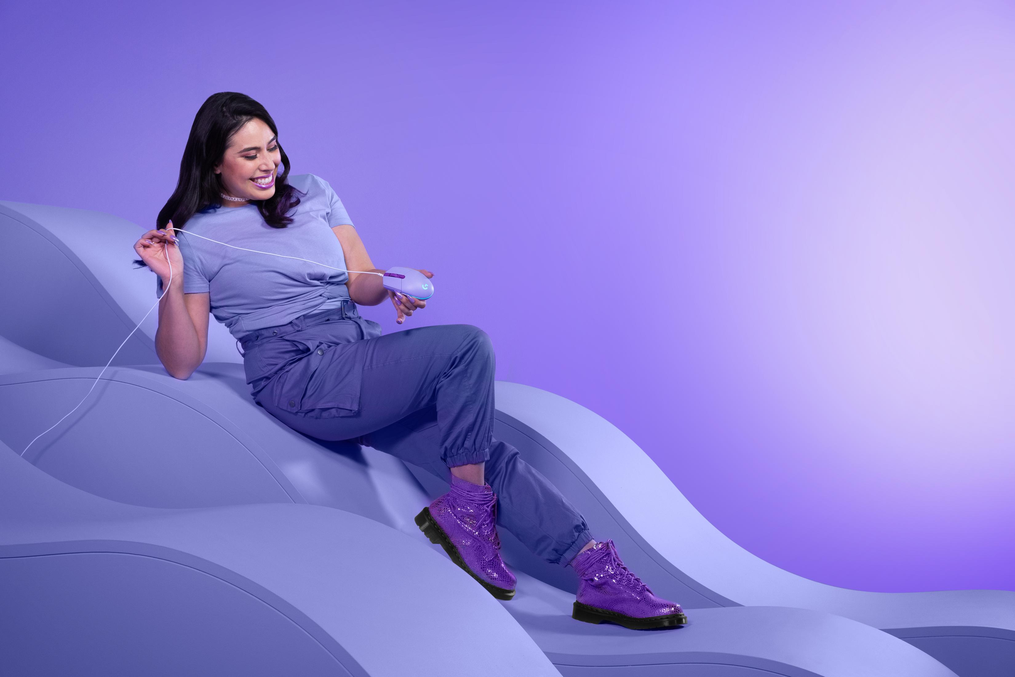 Kobieta z fioletową myszką i kablem siedzi na fioletowych falach.