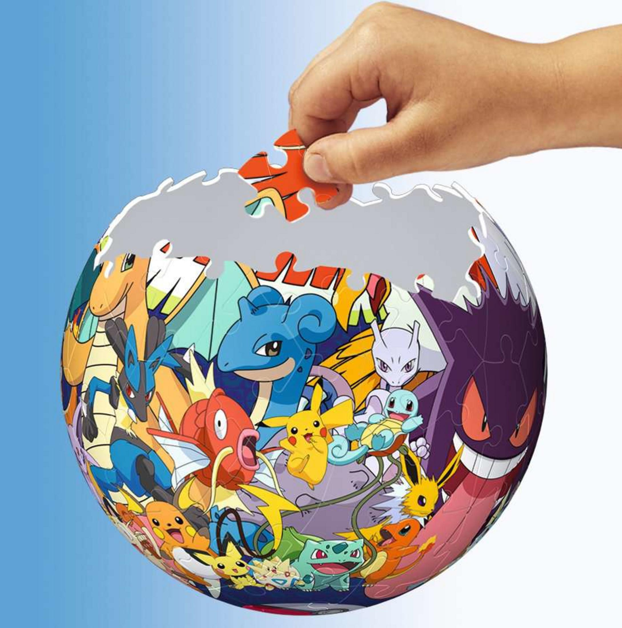 Een hand plaatst een Pokémon-puzzelstuk op een bolvormige montage.