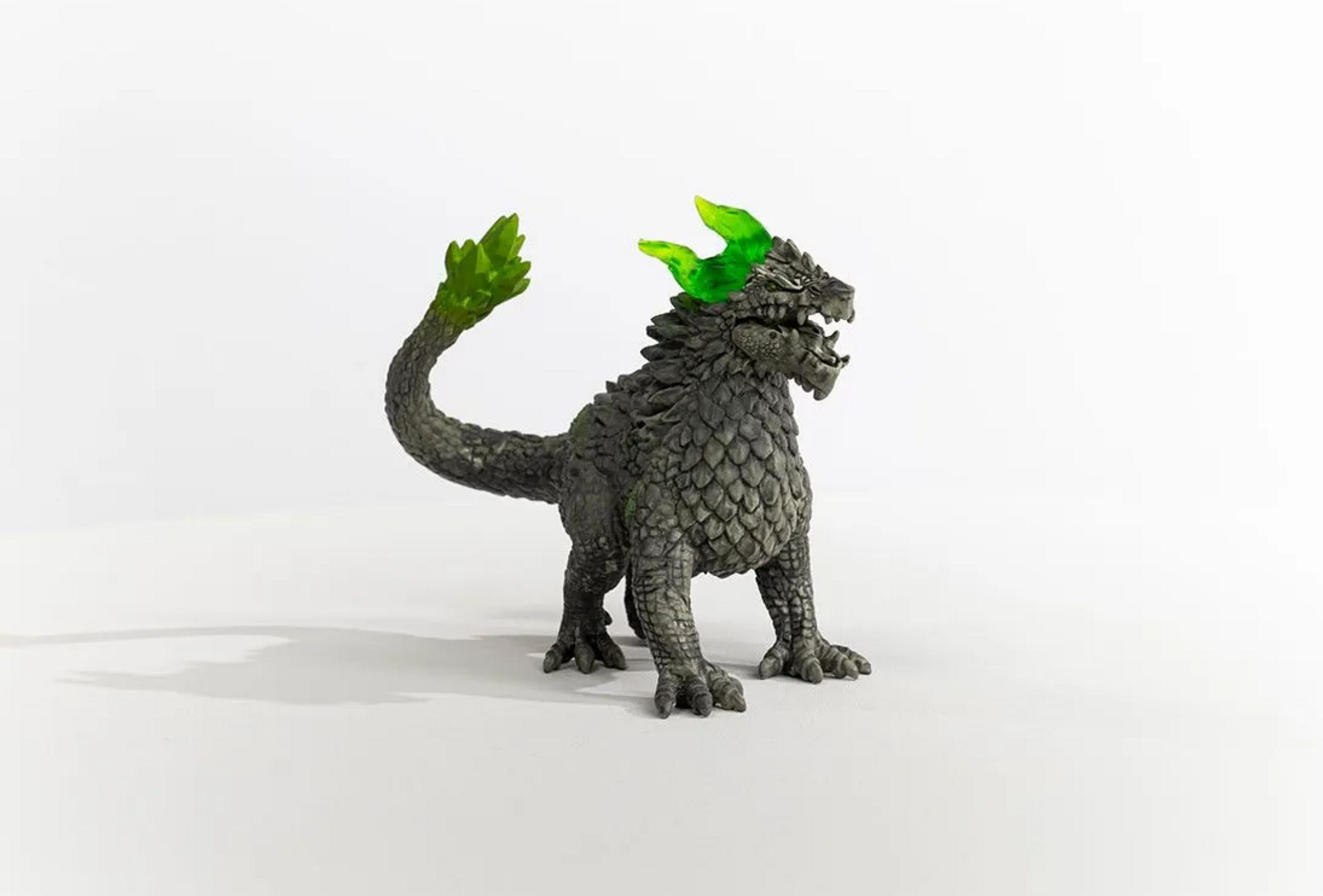 Szara figurka smoka z zielonymi rogami i końcówką ogona na białym tle.