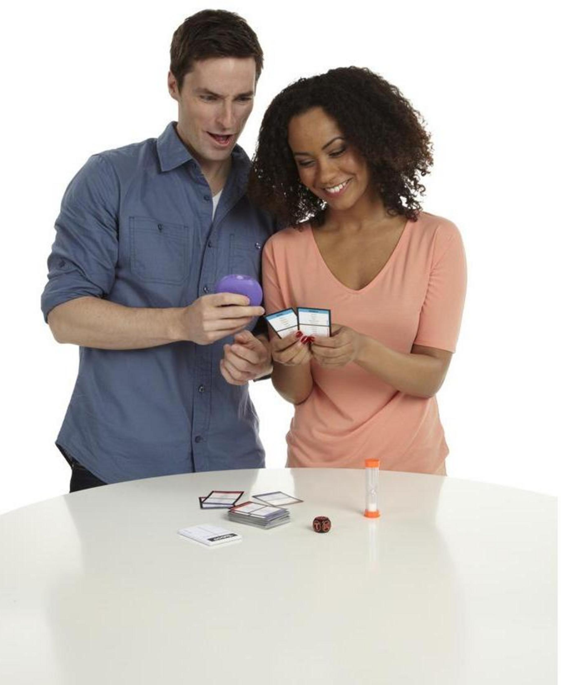 Ein Mann und eine Frau spielen ein Spiel mit Karten, einem Würfel und einer Sanduhr.