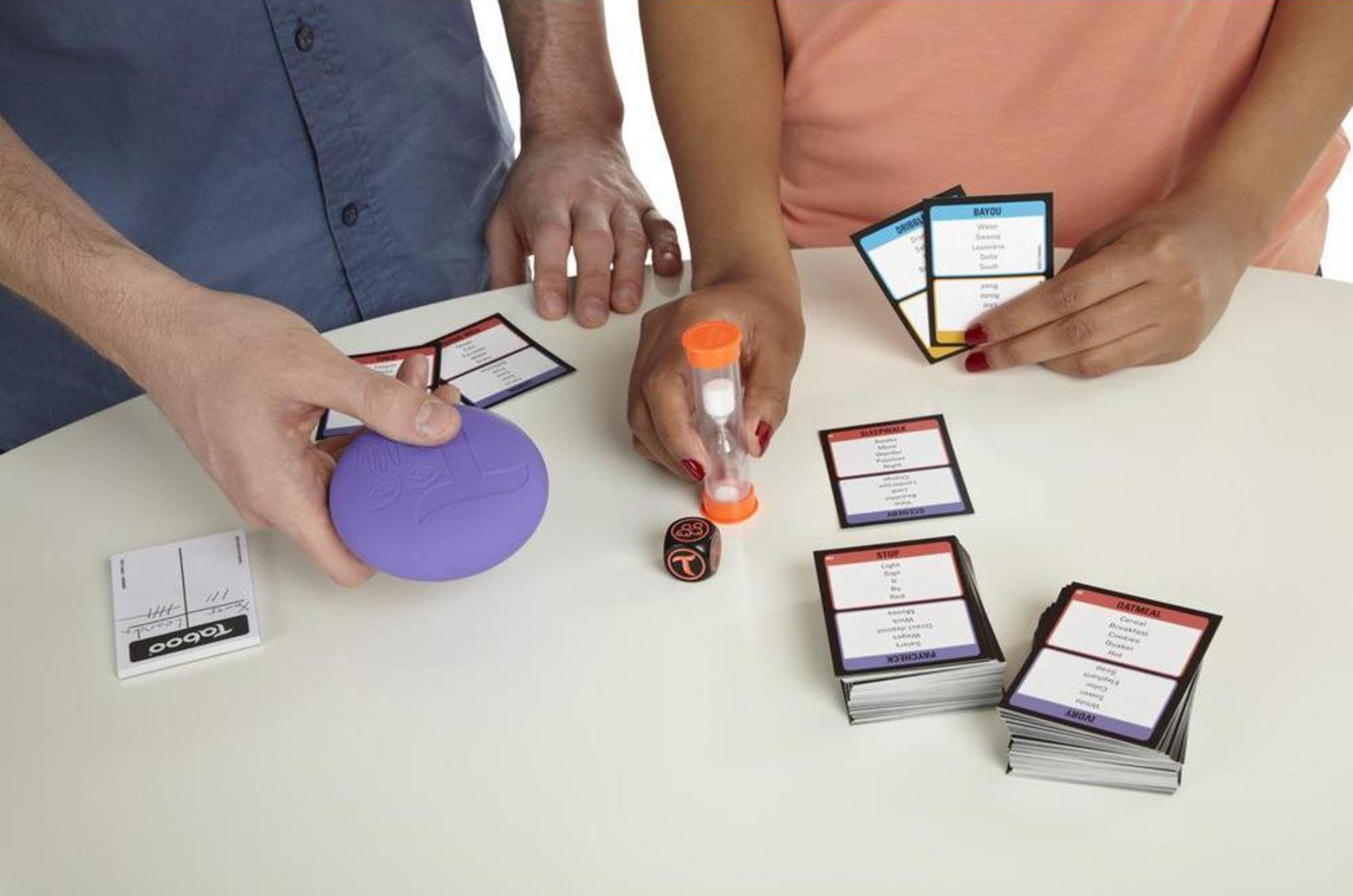 Personen spielen ein Spiel mit Karten, einem Würfel und einer Sanduhr.