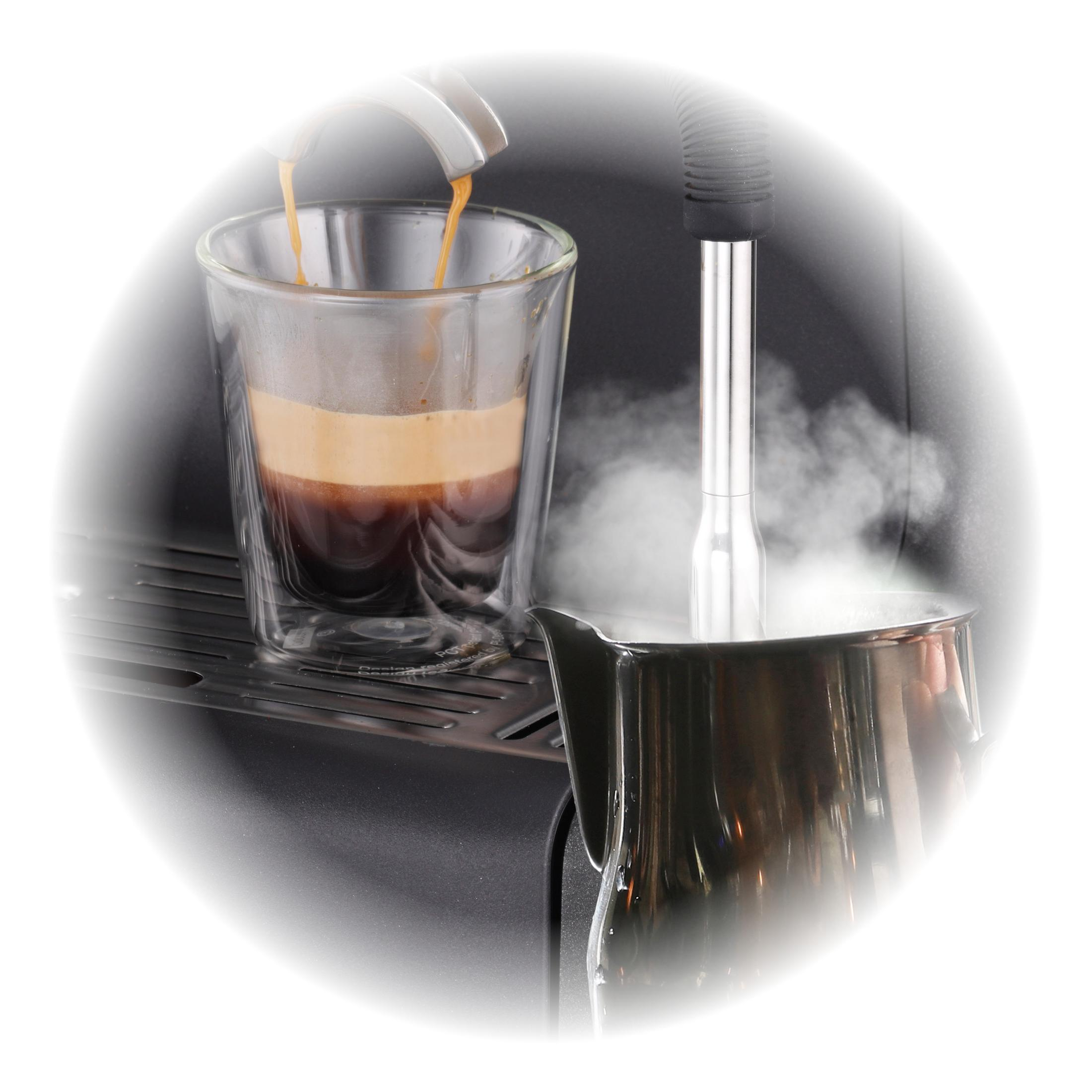 Espresso wird in ein Glas gegossen, Dampf steigt aus einem Metallkrug auf.