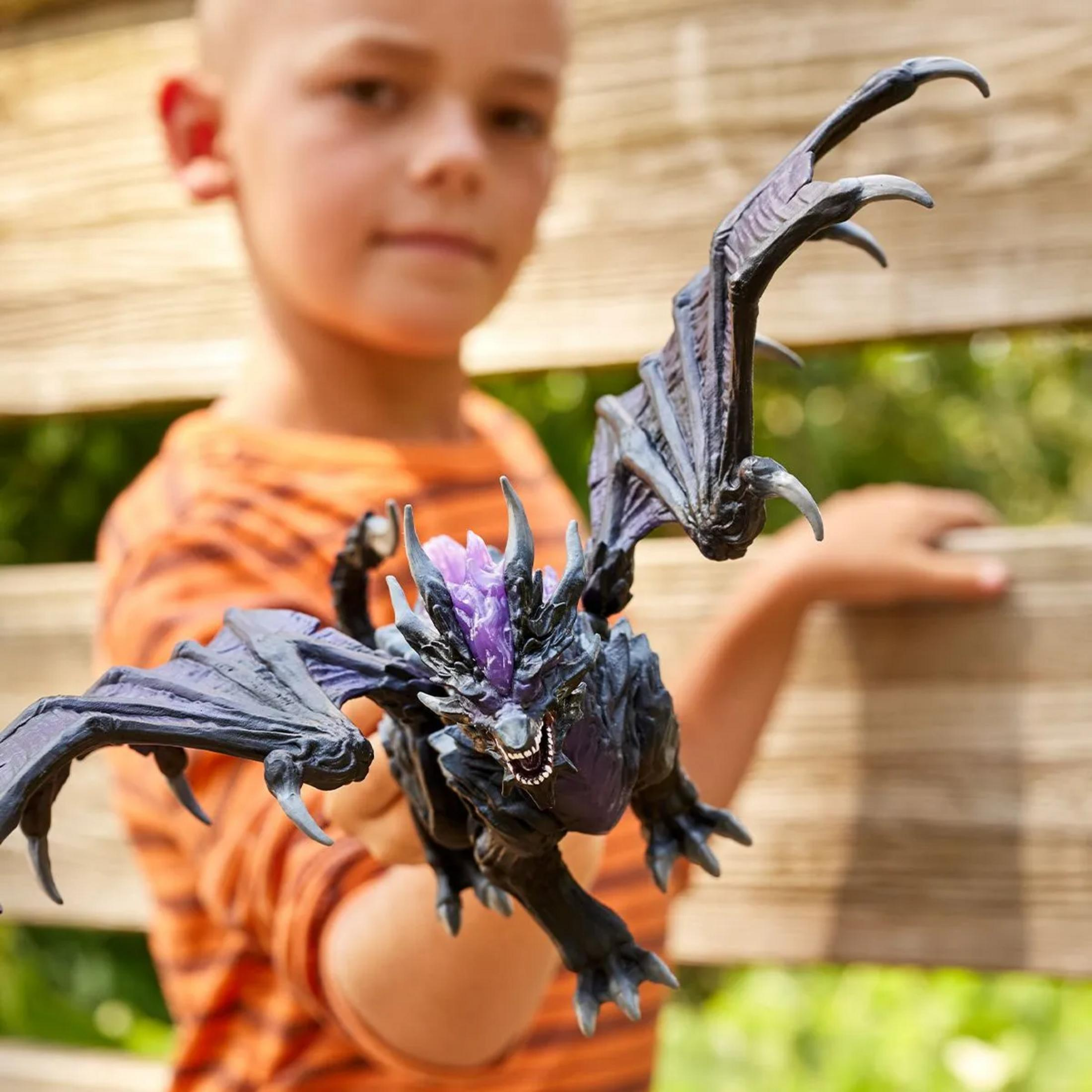 Un ragazzo tiene un giocattolo drago scuro con cristalli viola.