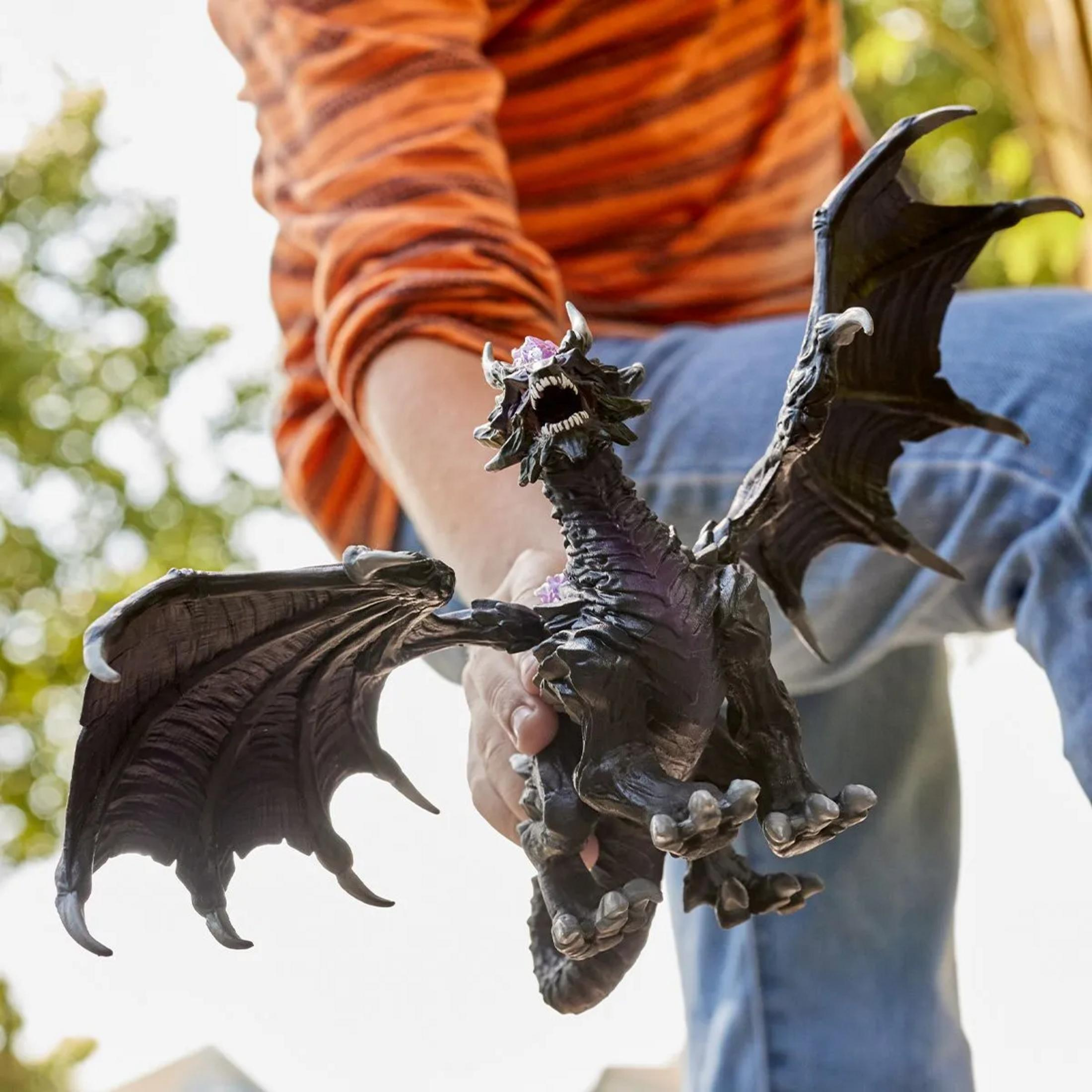 Una persona tiene una figura di drago nero con cristalli viola e ali spiegate.
