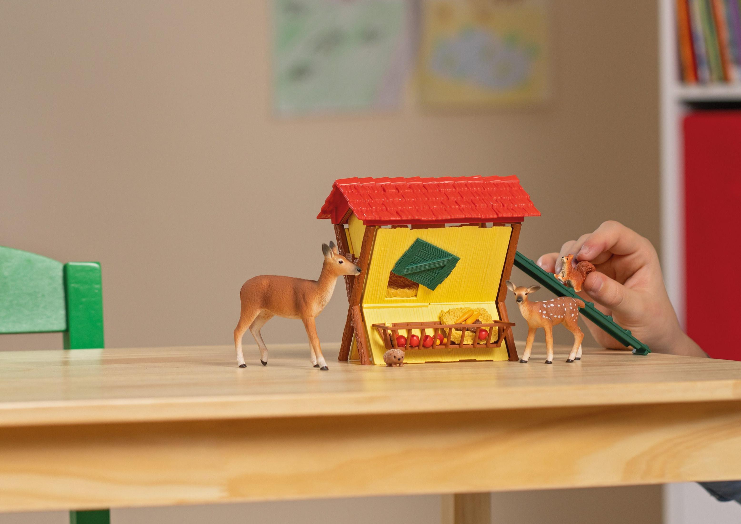 Spielzeug-Bauernhof mit Rehen, Eichhörnchen und Igel. Kind spielt.