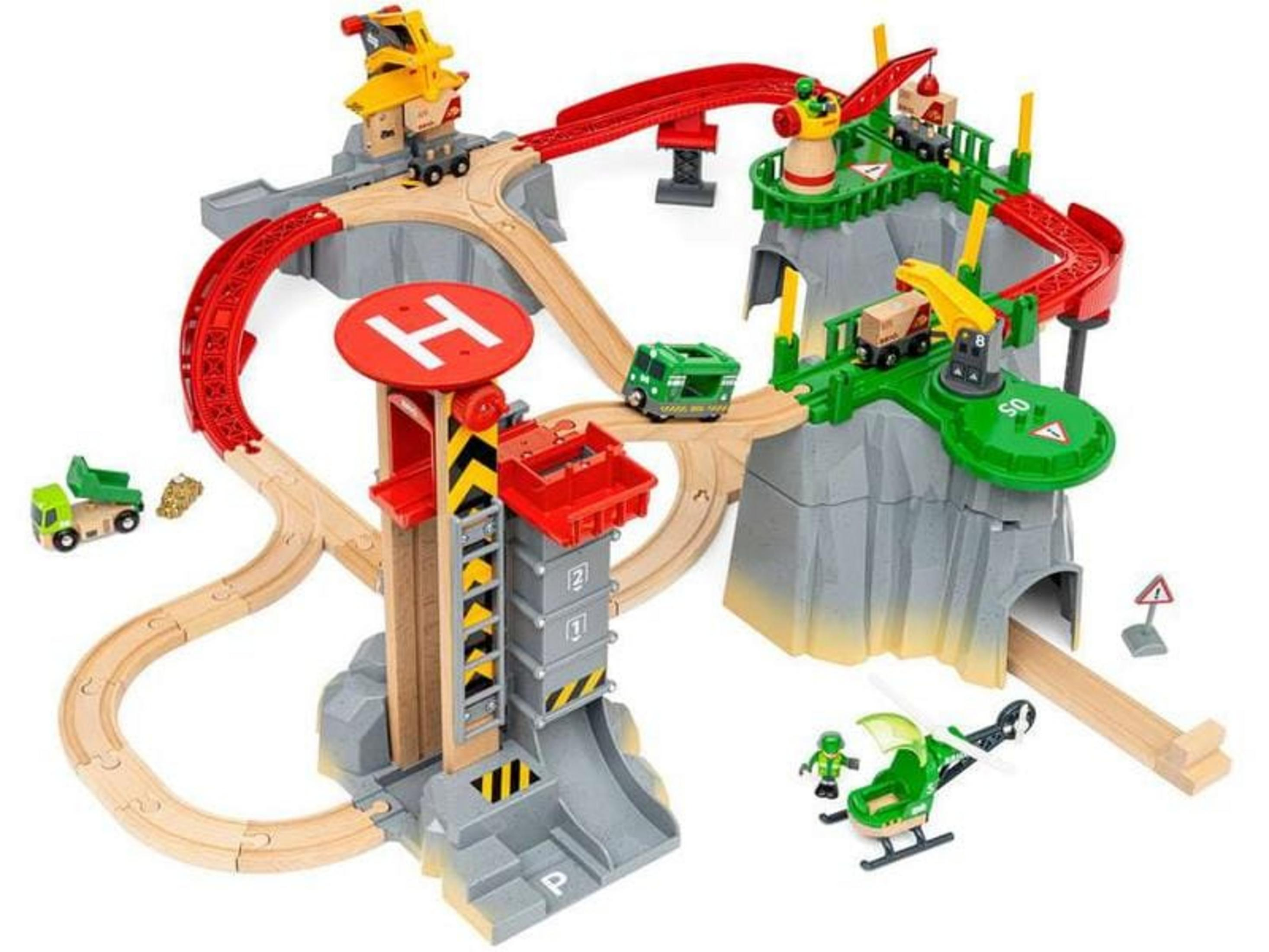 Eine Spielzeug-Eisenbahnlandschaft mit Holzschienen, Zügen, Lastwagen und Hubschrauber.