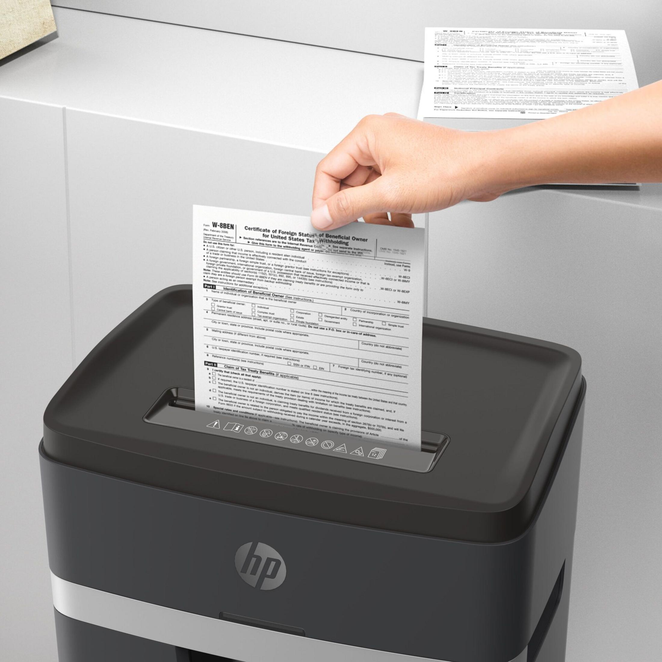 Una mano inserisce un documento in un distruggidocumenti HP.