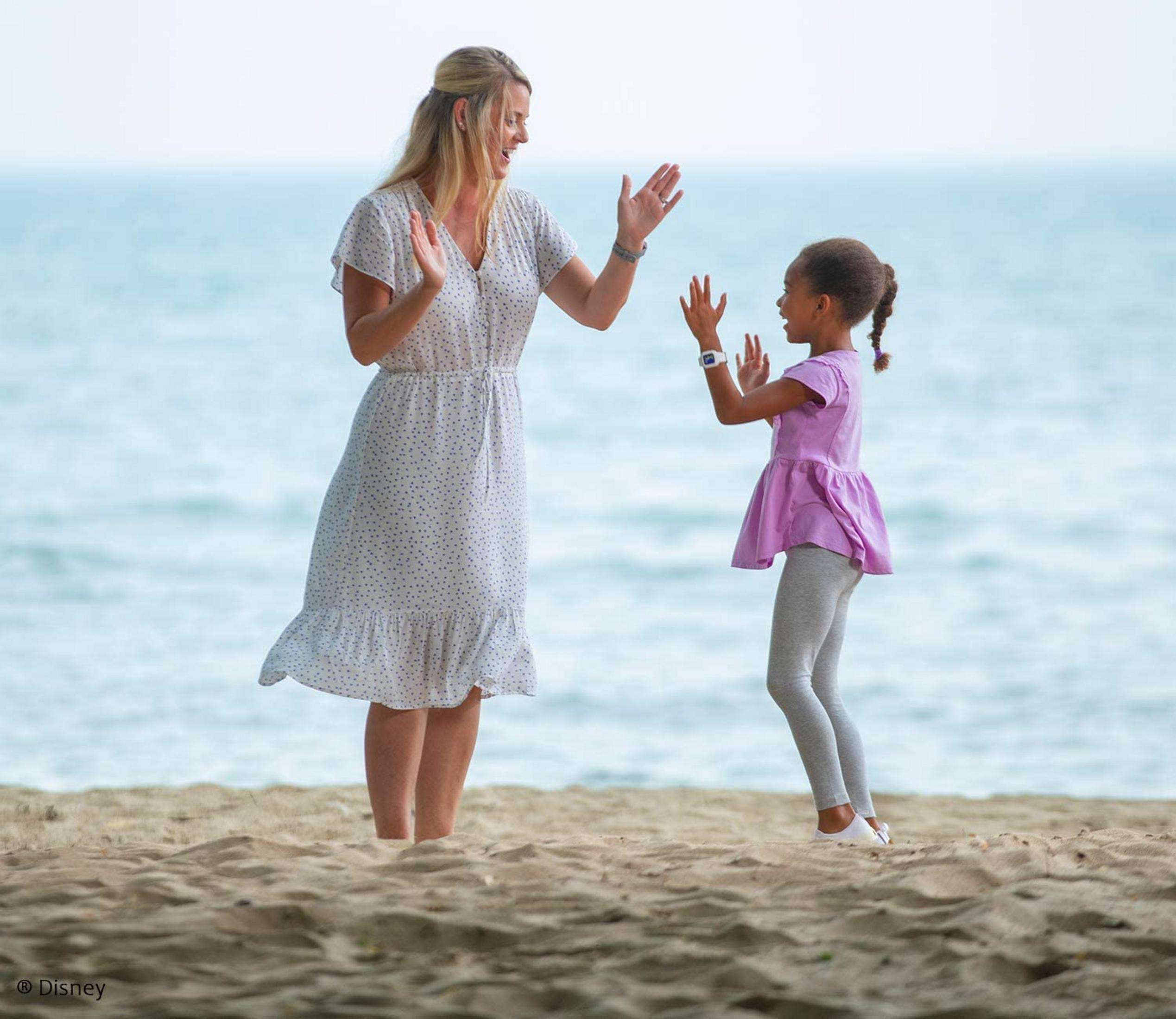 Kobieta i dziecko dają sobie piątkę na plaży przy oceanie.