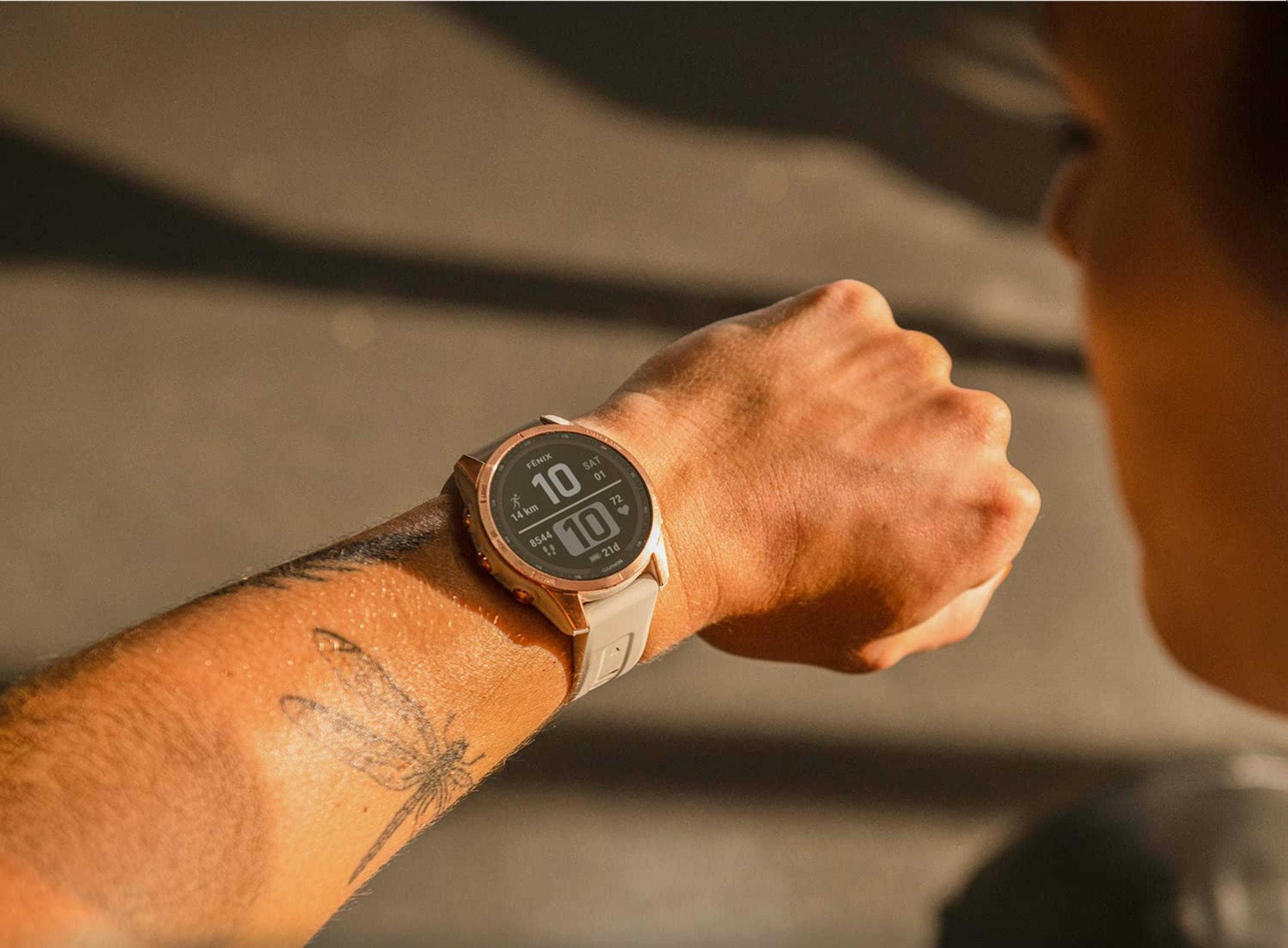 Nahaufnahme einer Person, die auf ihre Uhr schaut, mit einer Libellen-Tätowierung am Arm.