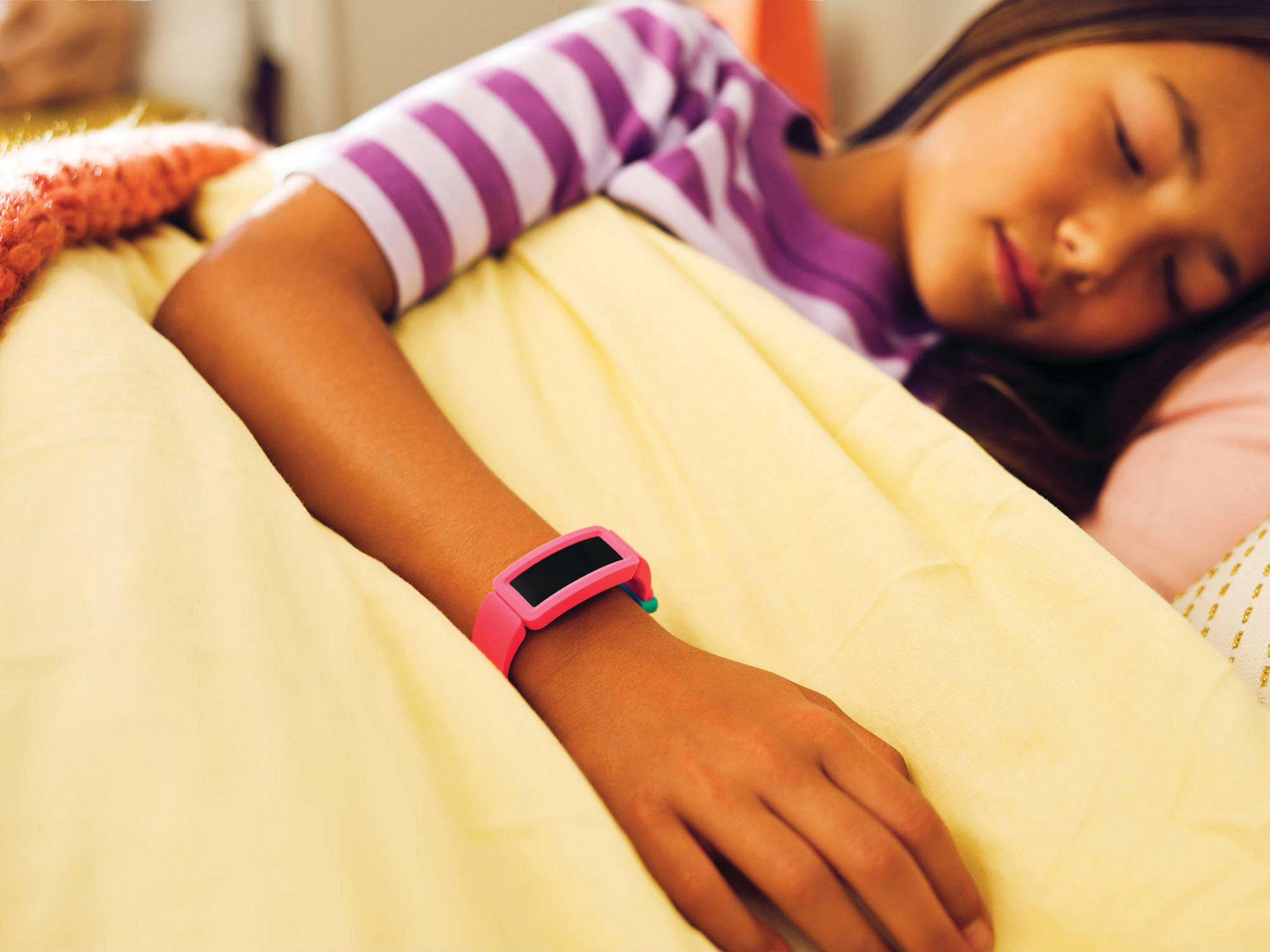 Ein Mädchen schläft in gestreifter Kleidung mit einem pinken Armband.
