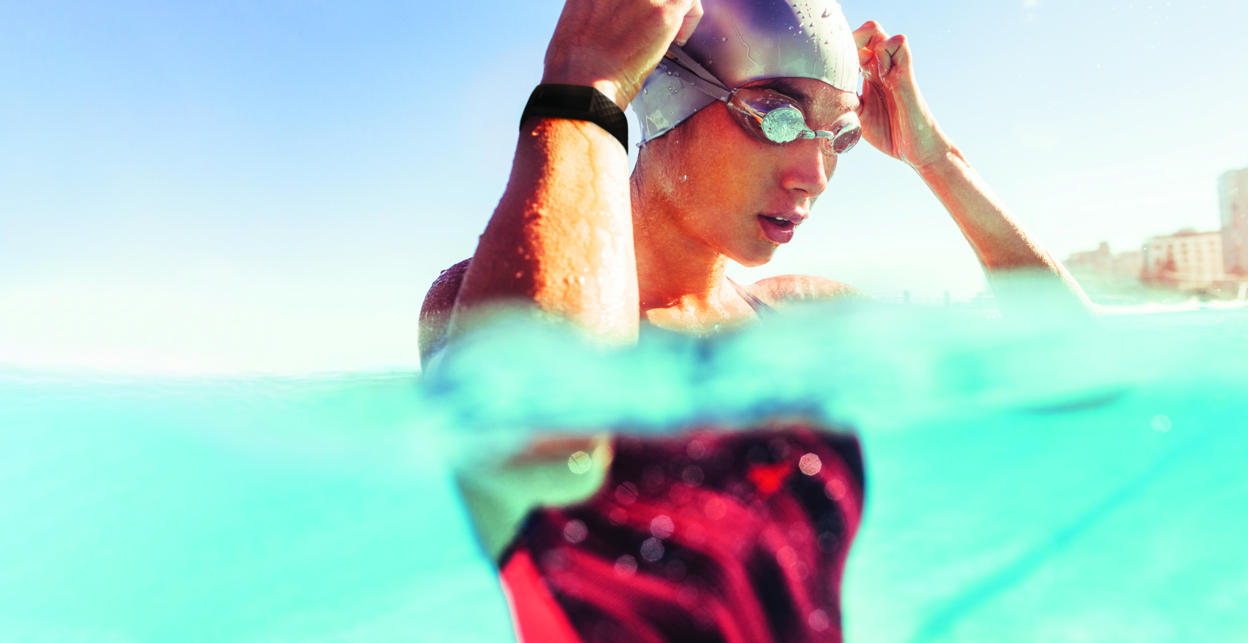 Schwimmerin mit Brille und Kappe im Wasser, stellt sich auf Wettkampf ein.