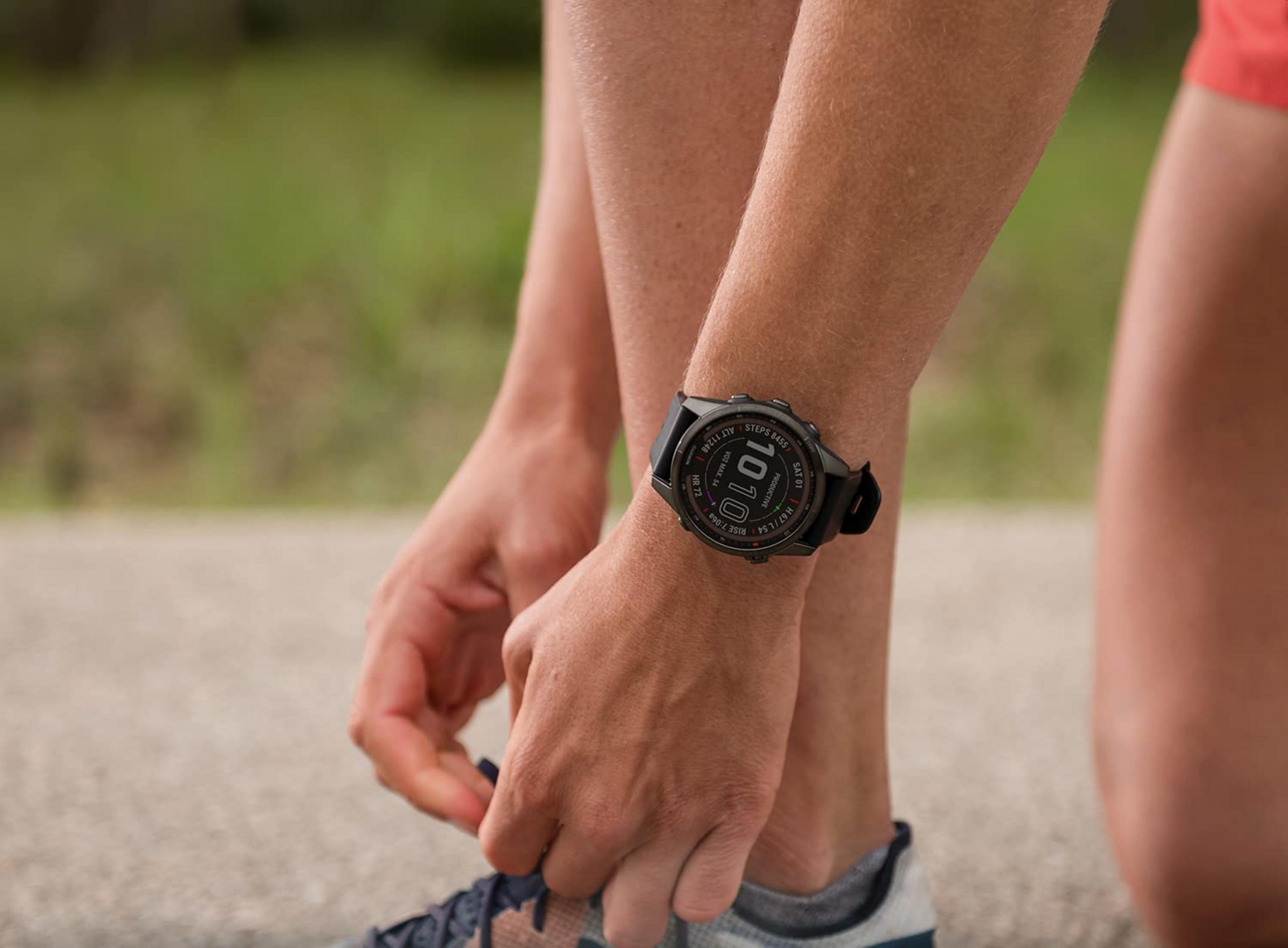 Eine Person schnürt ihre Laufschuhe, eine Smartwatch am Handgelenk.