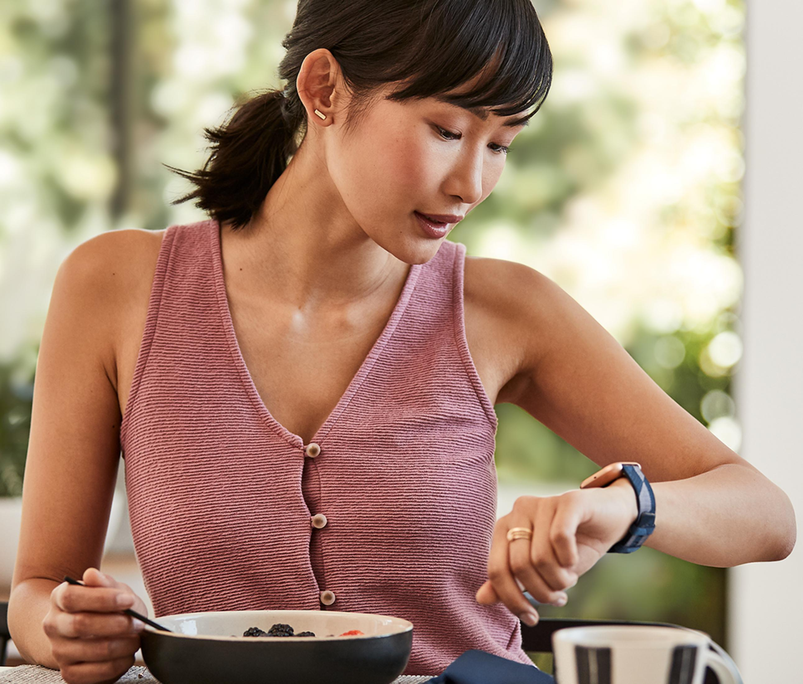 Une femme prend son petit-déjeuner et regarde sa montre.