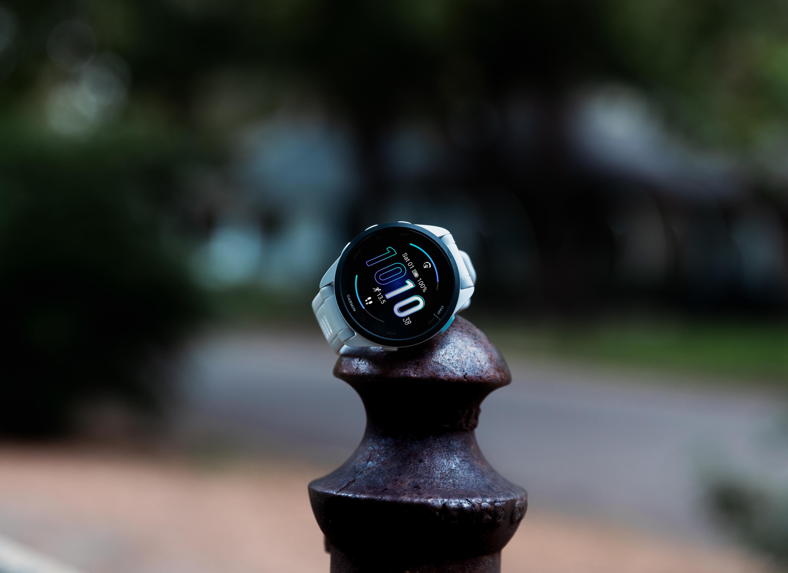 Een wit smartwatch met blauw display op een roestige metalen paal buiten.