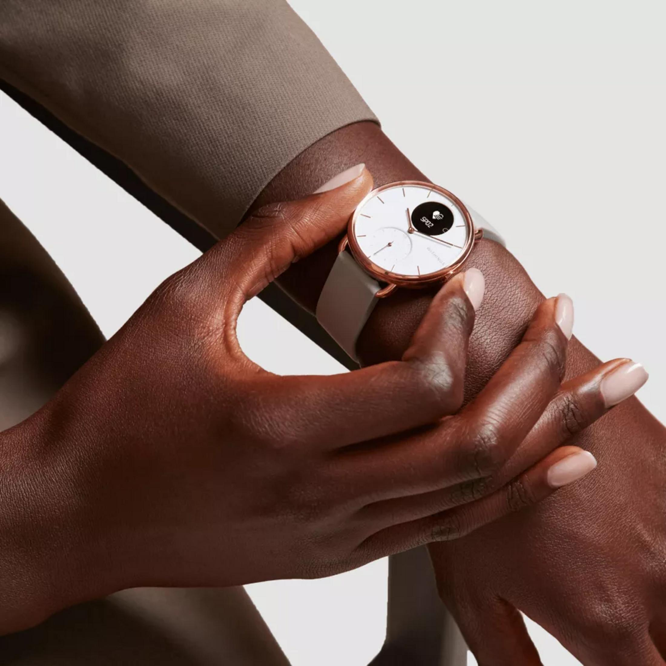 Eine Person trägt eine Smartwatch am Handgelenk. Die Uhr hat ein weißes Zifferblatt.