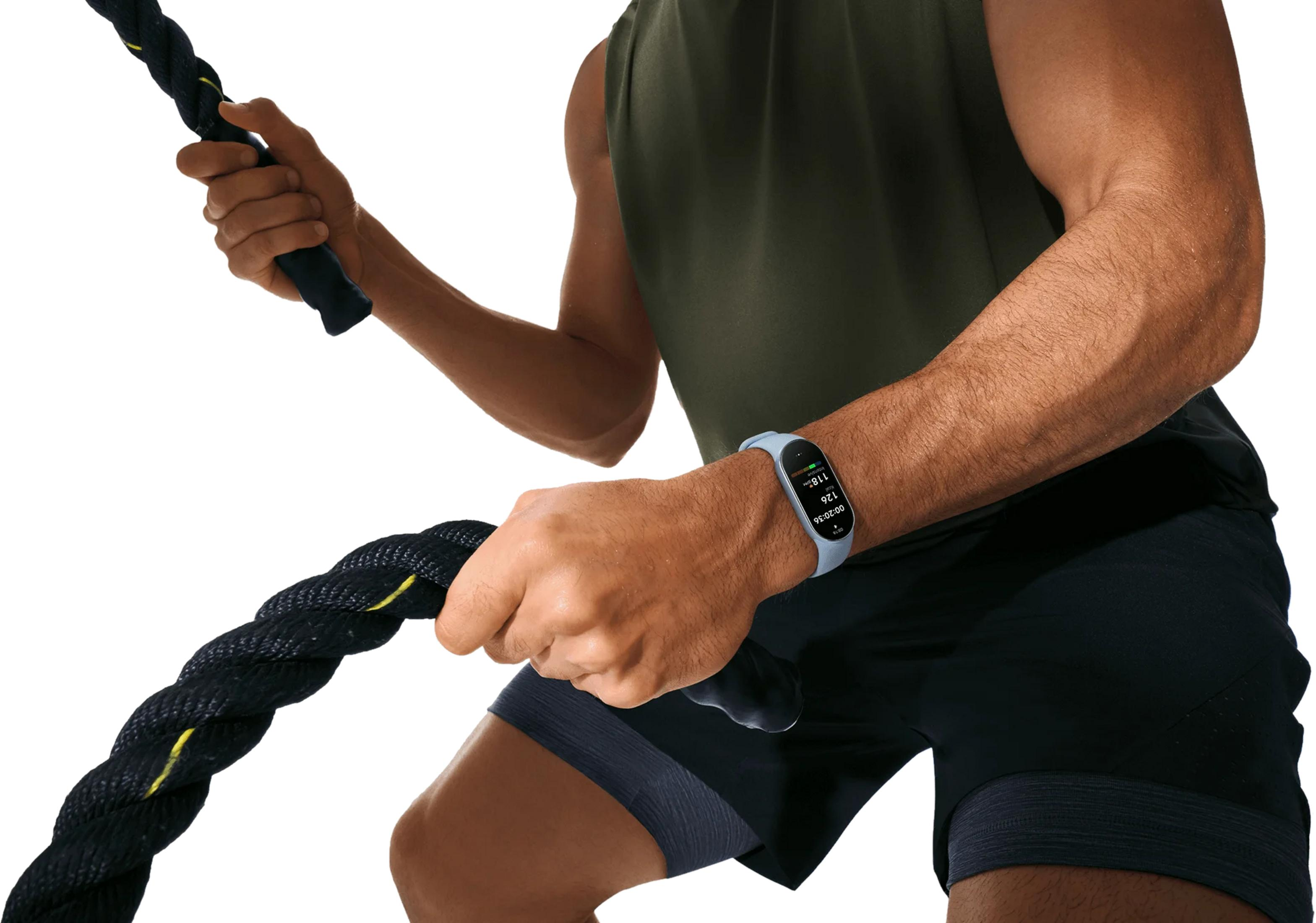 Mężczyzna z liną treningową i zegarkiem fitness, ubrany na czarno i zielono.