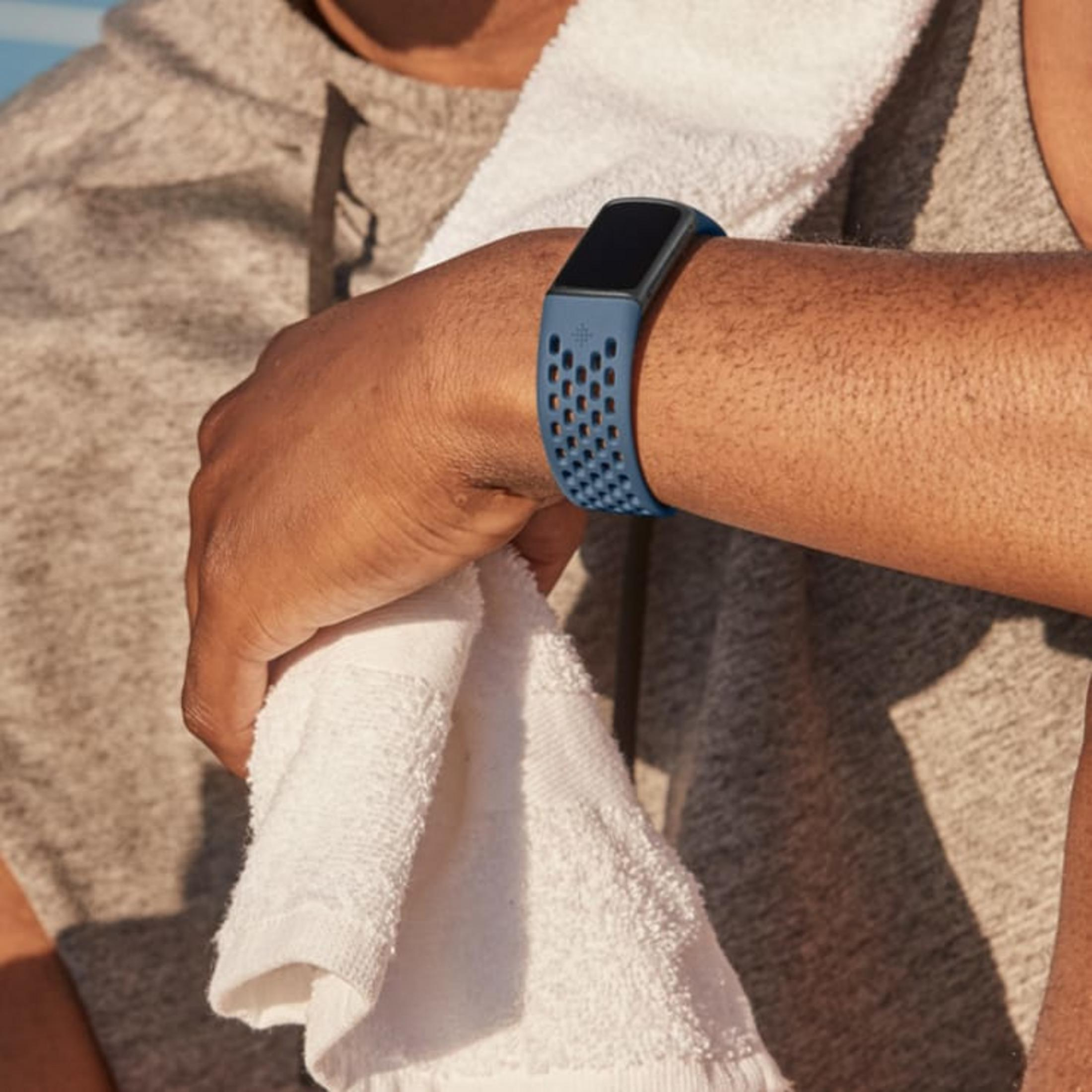 Eine Person mit einem blauen Fitness-Tracker und einem Handtuch.