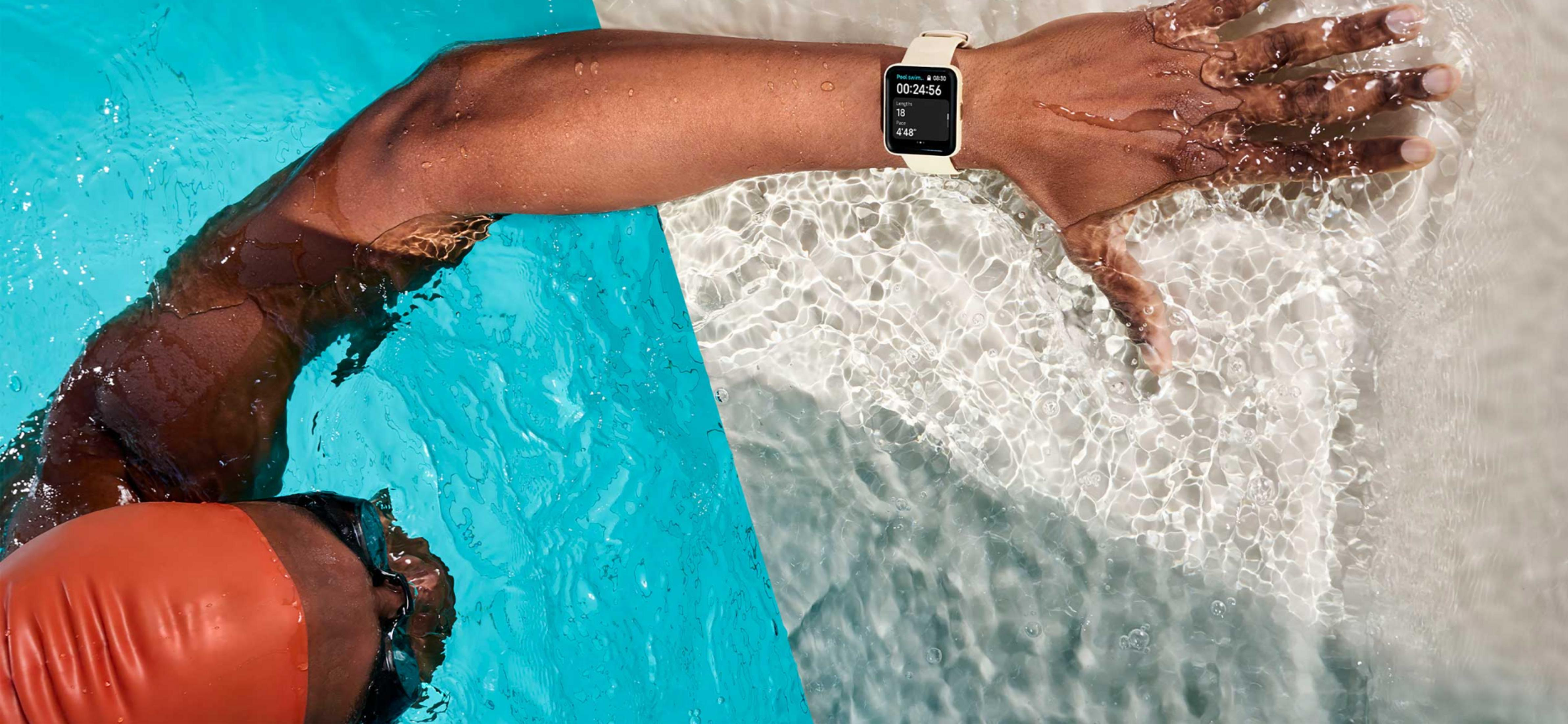 Nuotatore con cuffia e orologio in piscina, braccio in acqua.