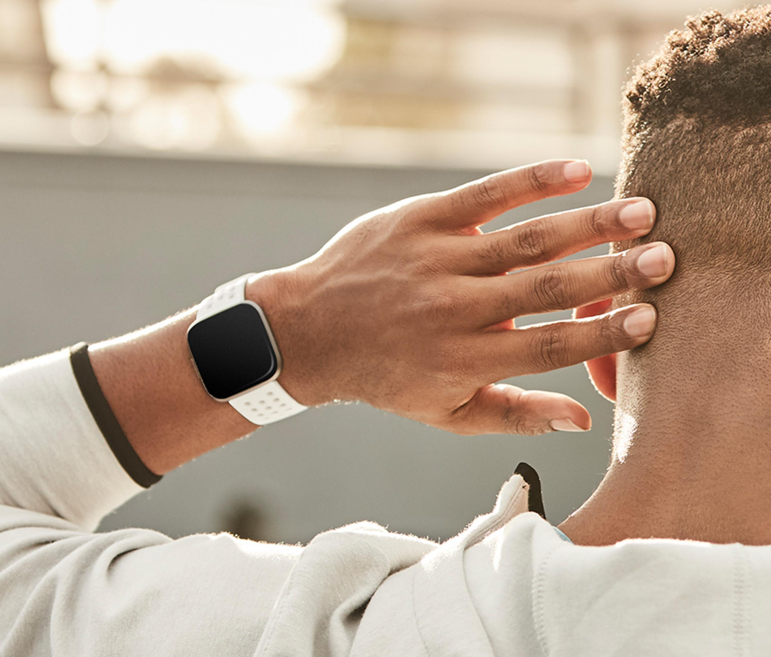 Ein Mann mit weißer Smartwatch am Handgelenk, seine Hand am Kopf.