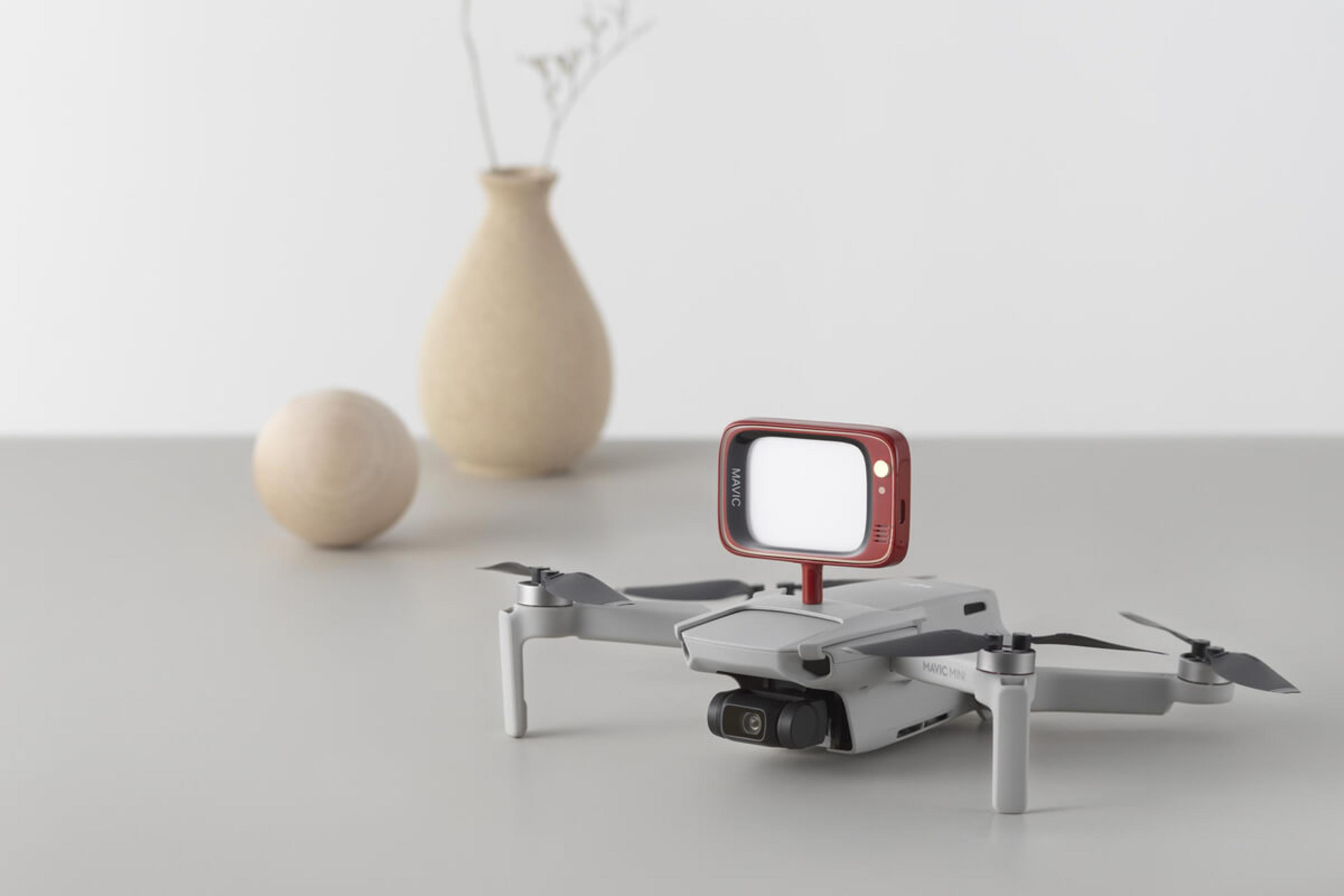 Eine weiße Drohne mit einem roten Mini-Fernseher-Aufsatz steht auf einem Tisch.