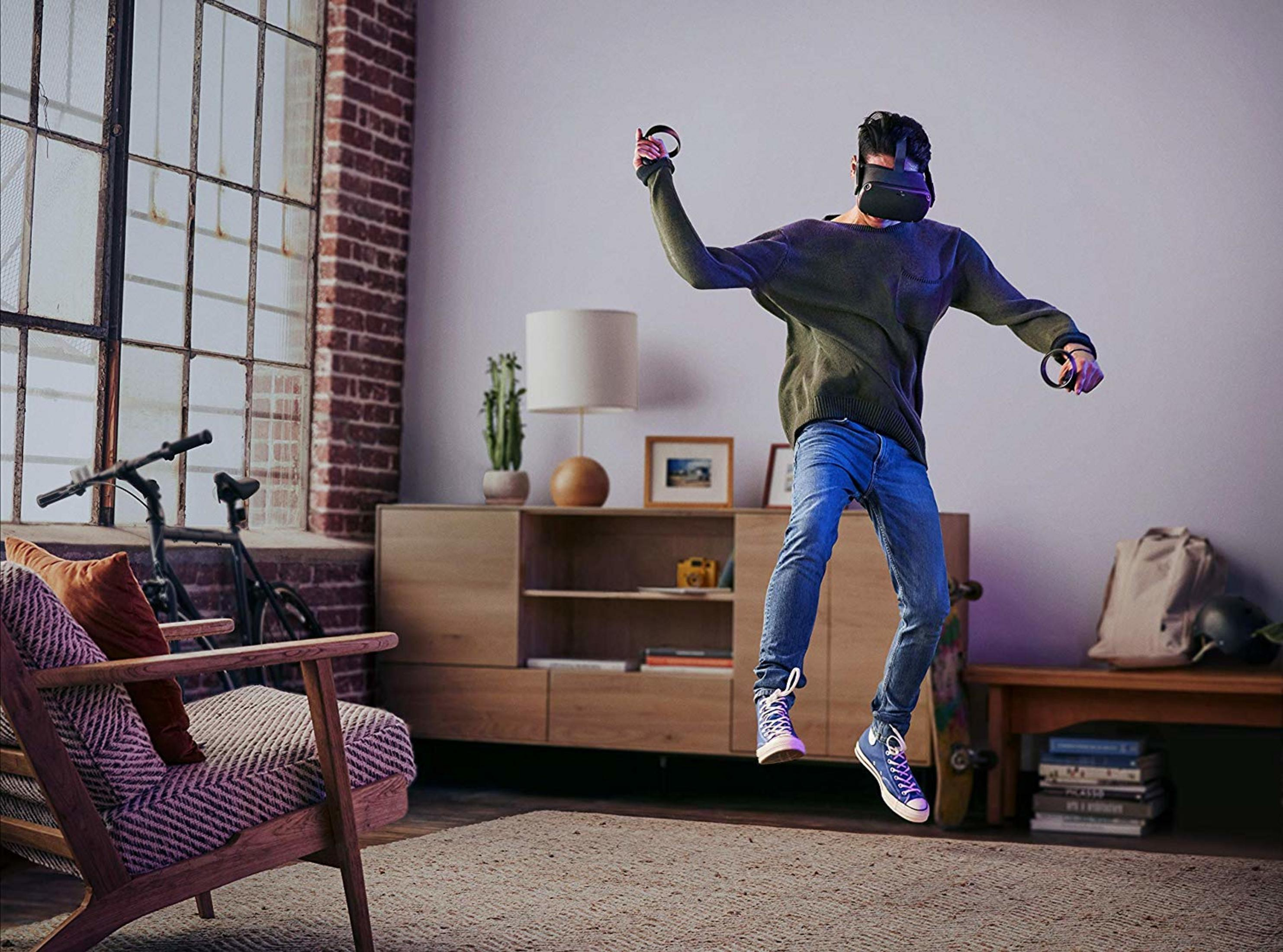 Mann in VR-Brille springt in einem Wohnzimmer mit Möbeln.