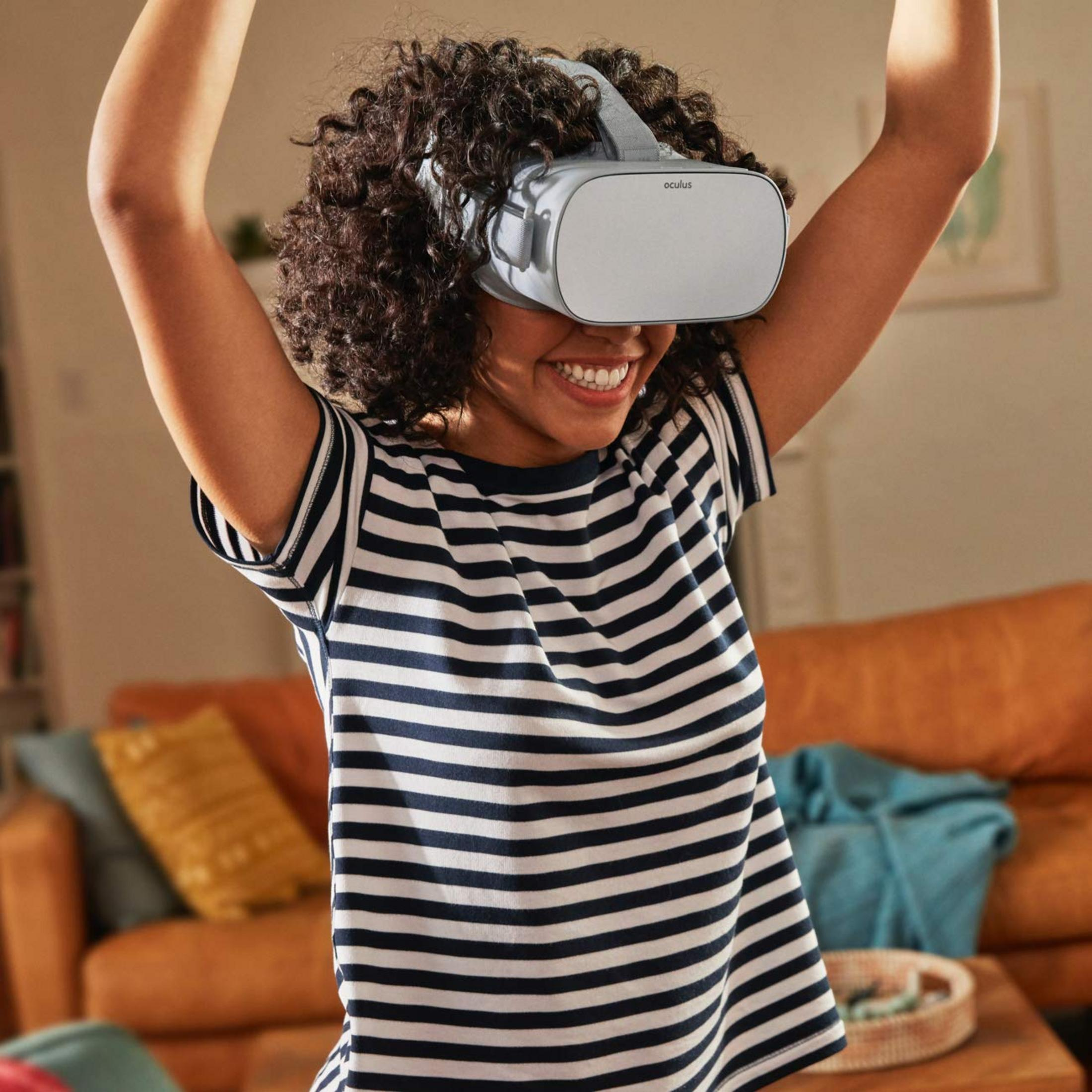 Eine Frau mit lockigem Haar trägt eine VR-Brille und ein gestreiftes Shirt.