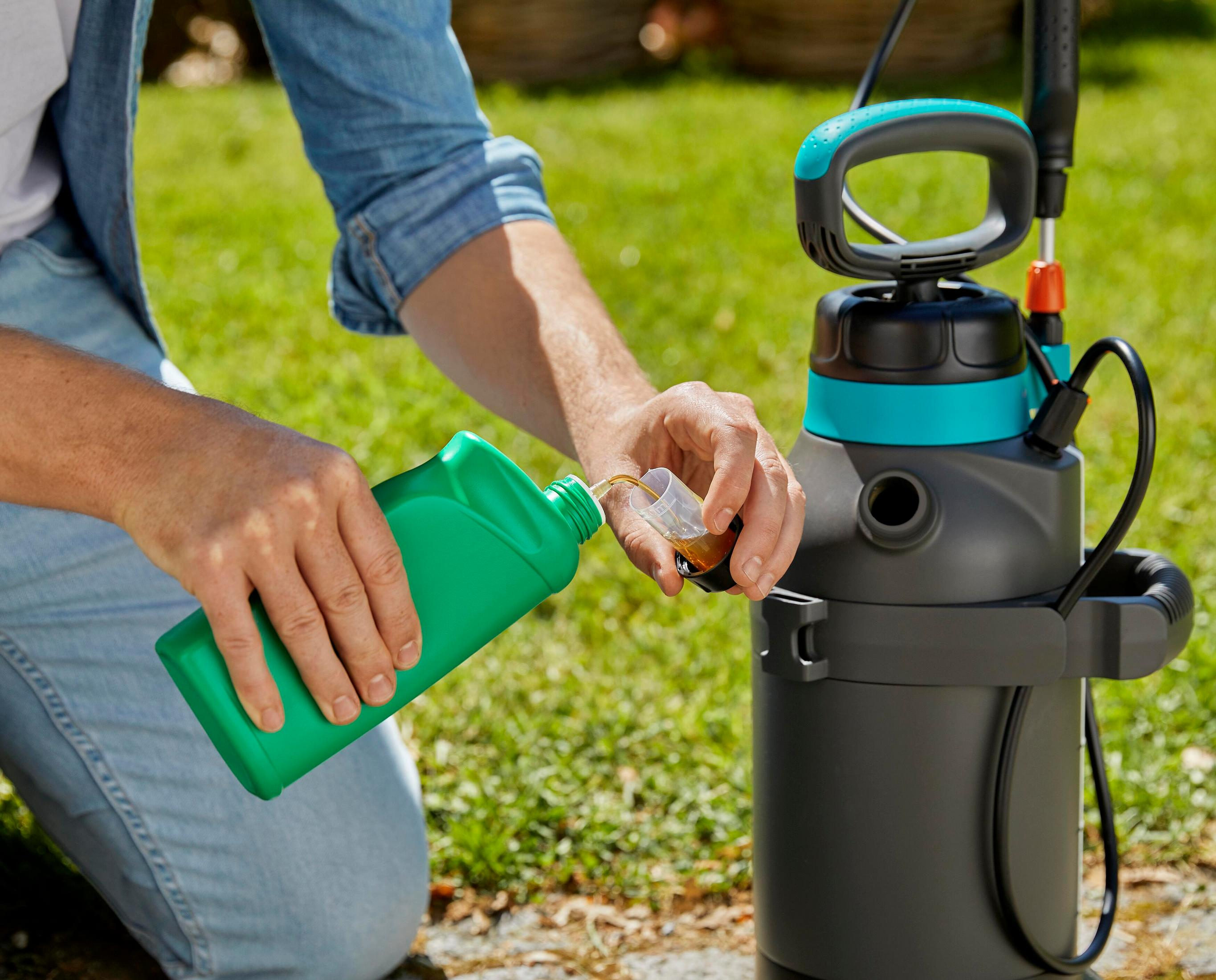 Mann gießt Flüssigkeit aus grüner Flasche in Sprühgerät-Messbecher.