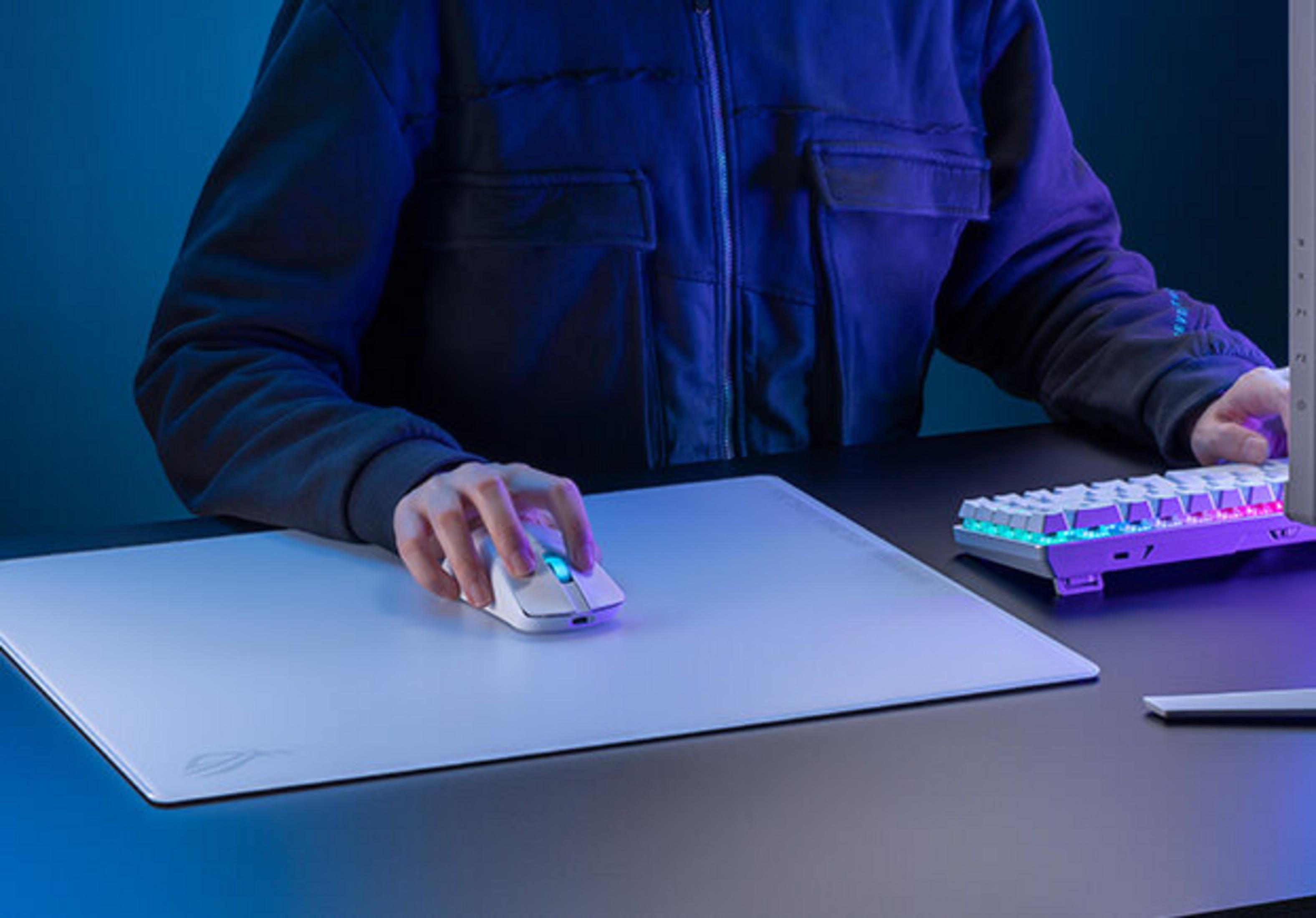 Osoba używa białej myszy na jasnej podkładce pod mysz obok klawiatury.