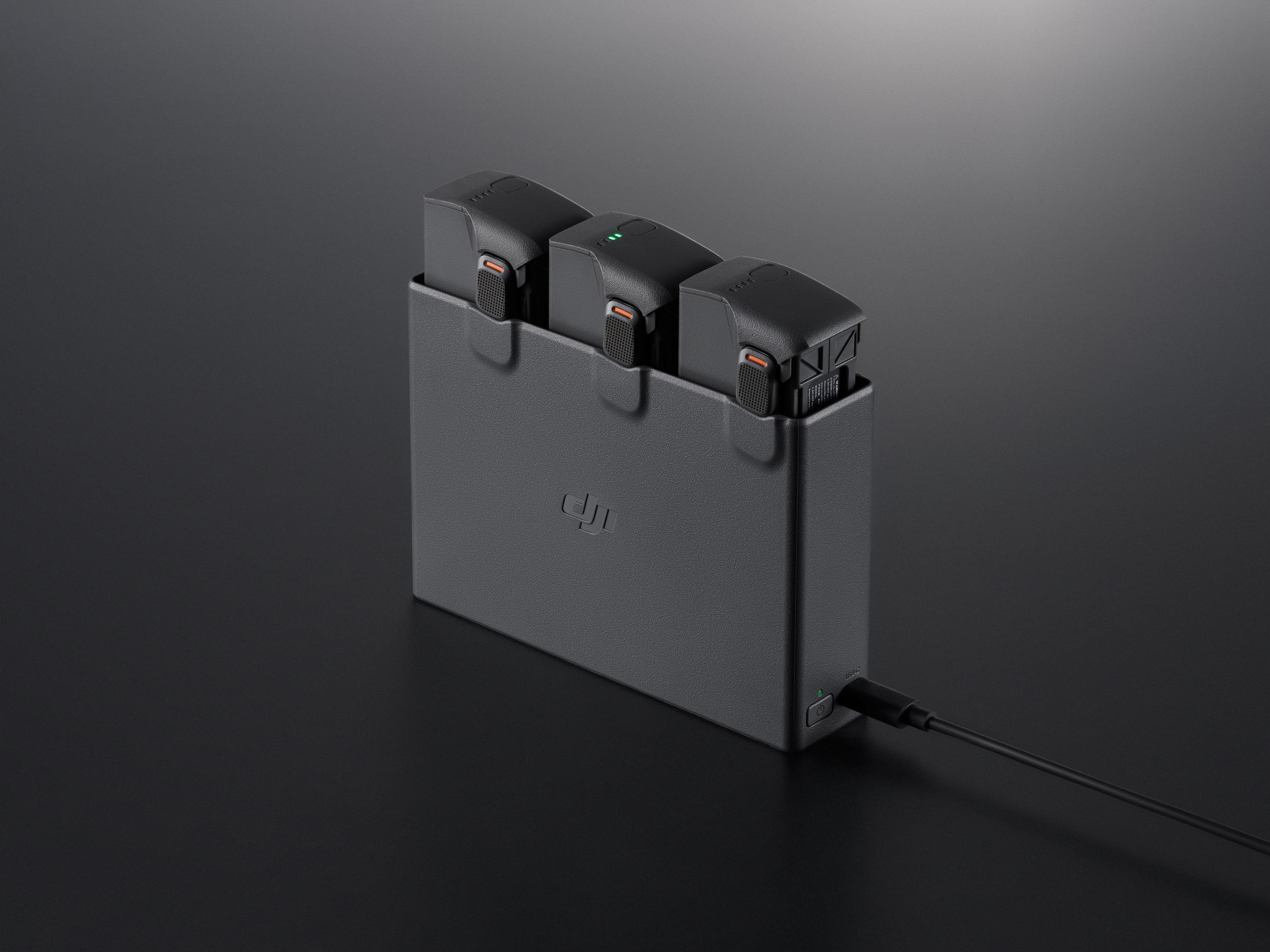 Hub di ricarica grigio con tre batterie per droni, un cavo collegato.