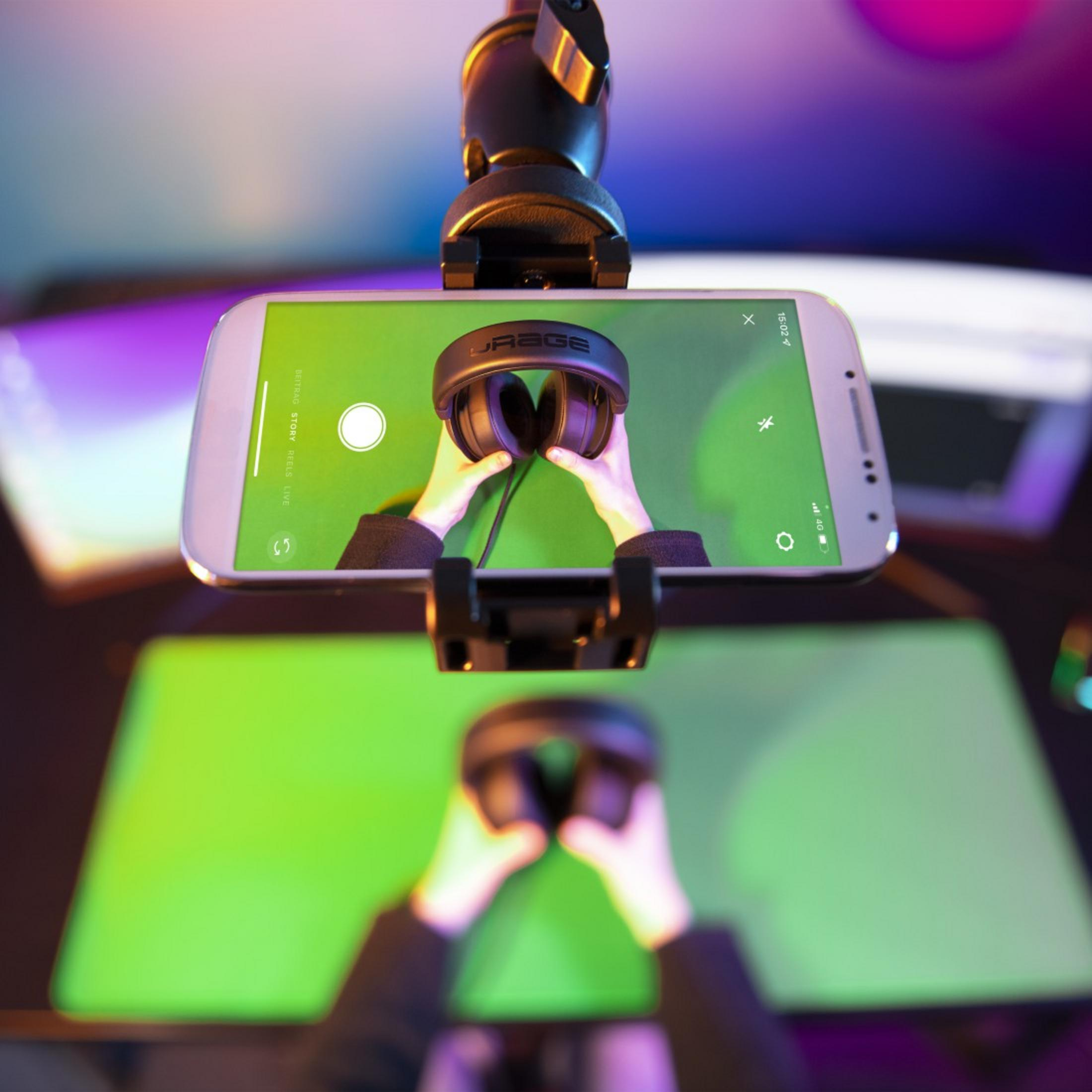 Hände halten Kopfhörer vor Handy-Bildschirm mit grüner Hintergrundbeleuchtung.