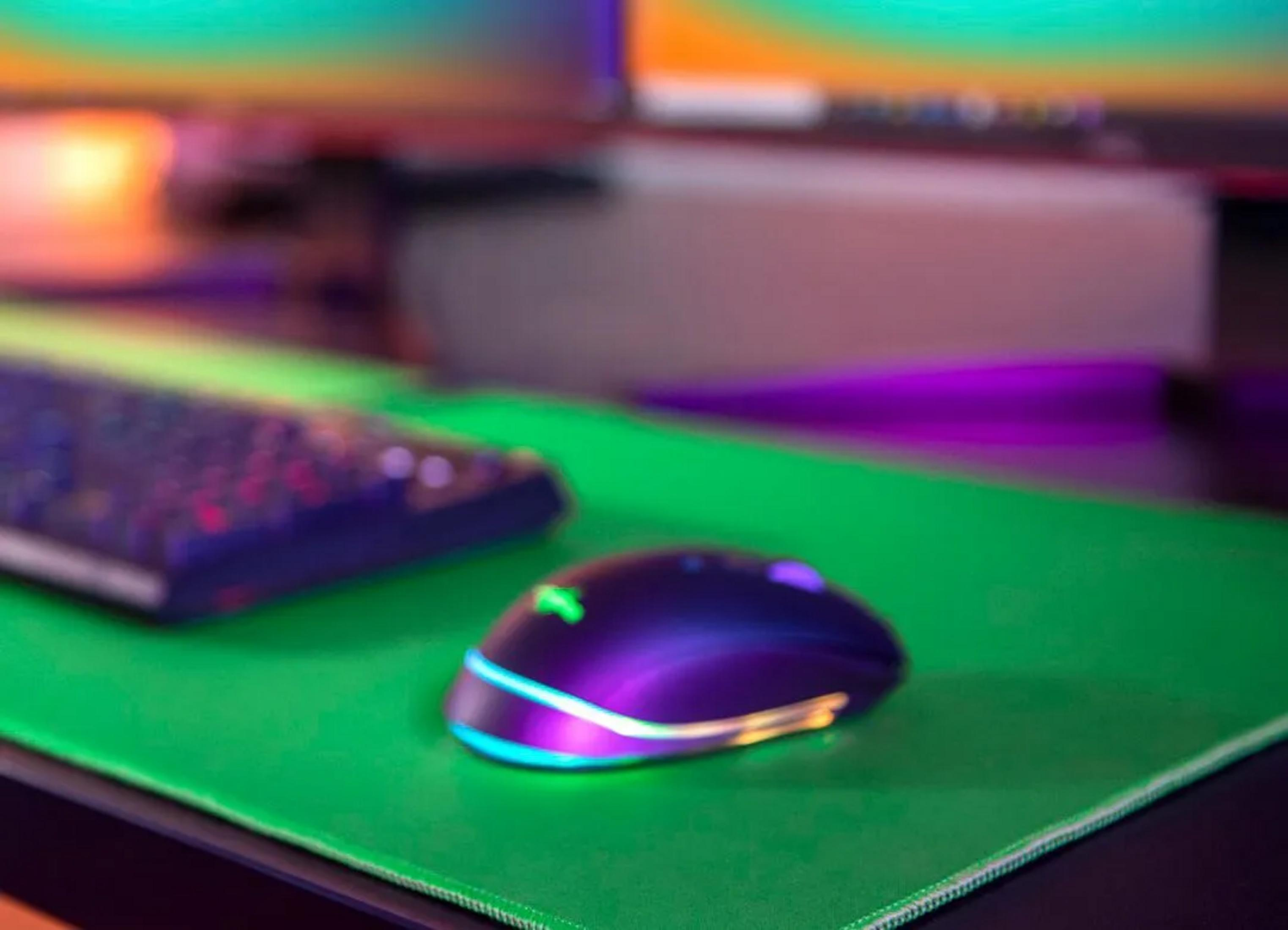 Eine violette Gaming-Maus mit RGB-Beleuchtung auf einer grünen Matte.