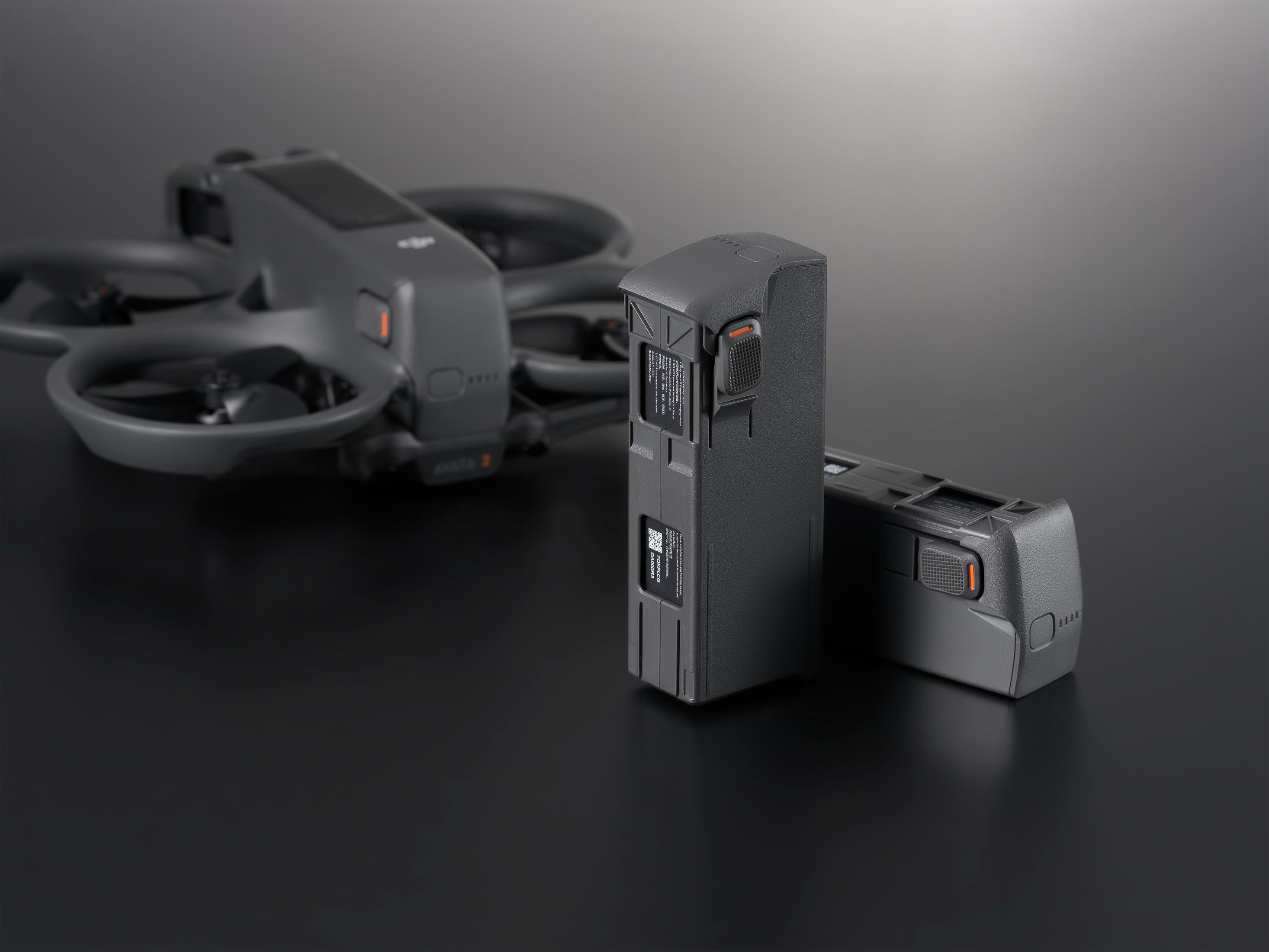 Batteria drone grigia con pulsante arancione su sfondo scuro.