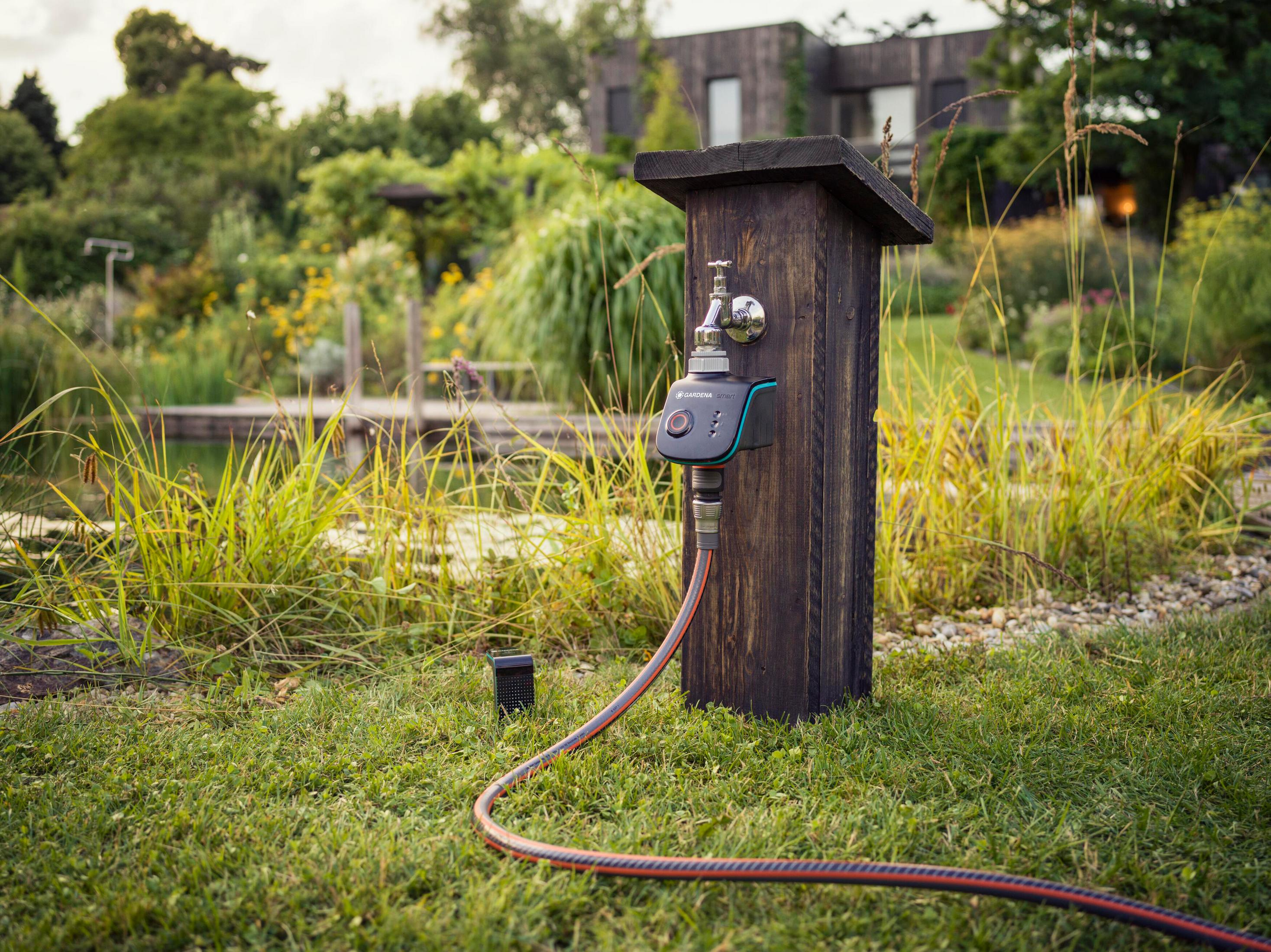 Ein Wasserhahn mit Zeitschaltuhr auf einem Holzkasten im Garten.