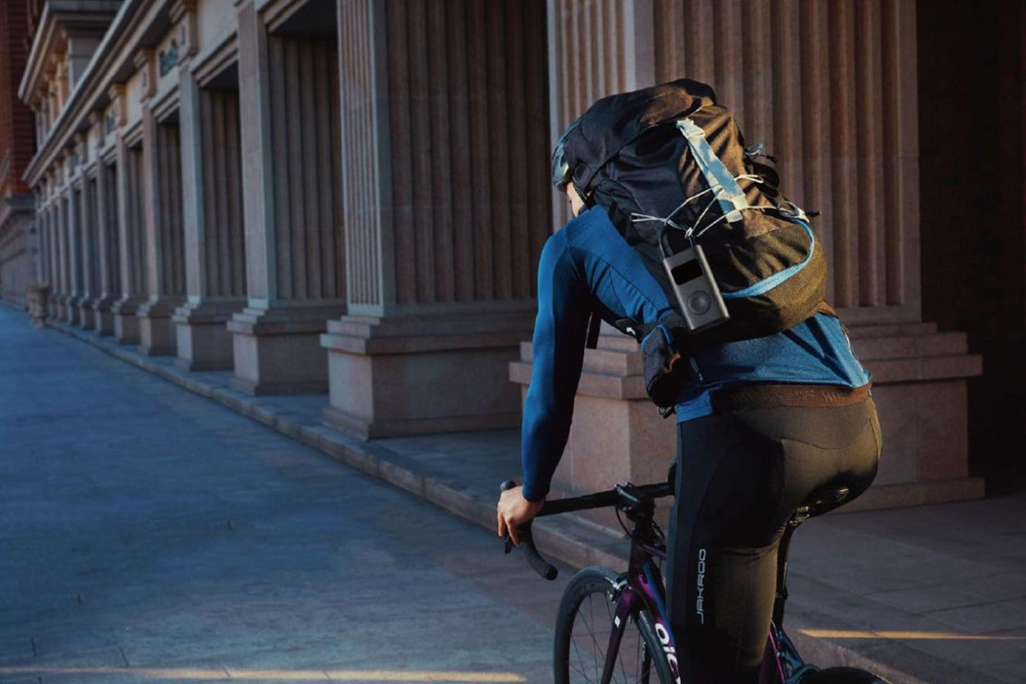 Ciclista con mochila pedalea junto a una hilera de columnas.