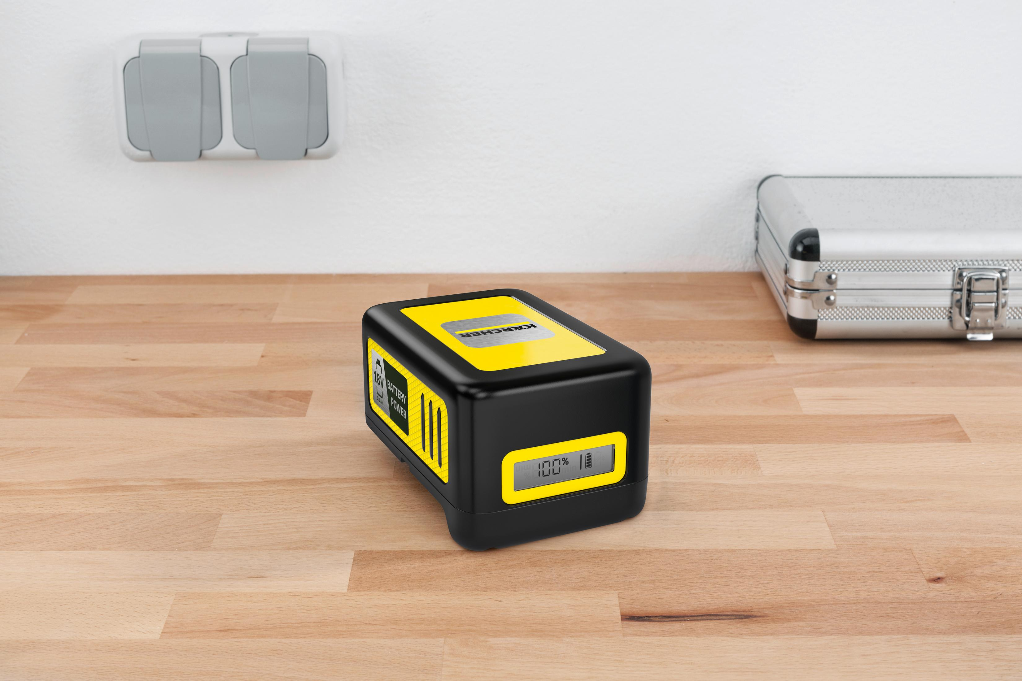 Schwarzer Akku mit gelben Akzenten und Digitalanzeige auf Holztisch.