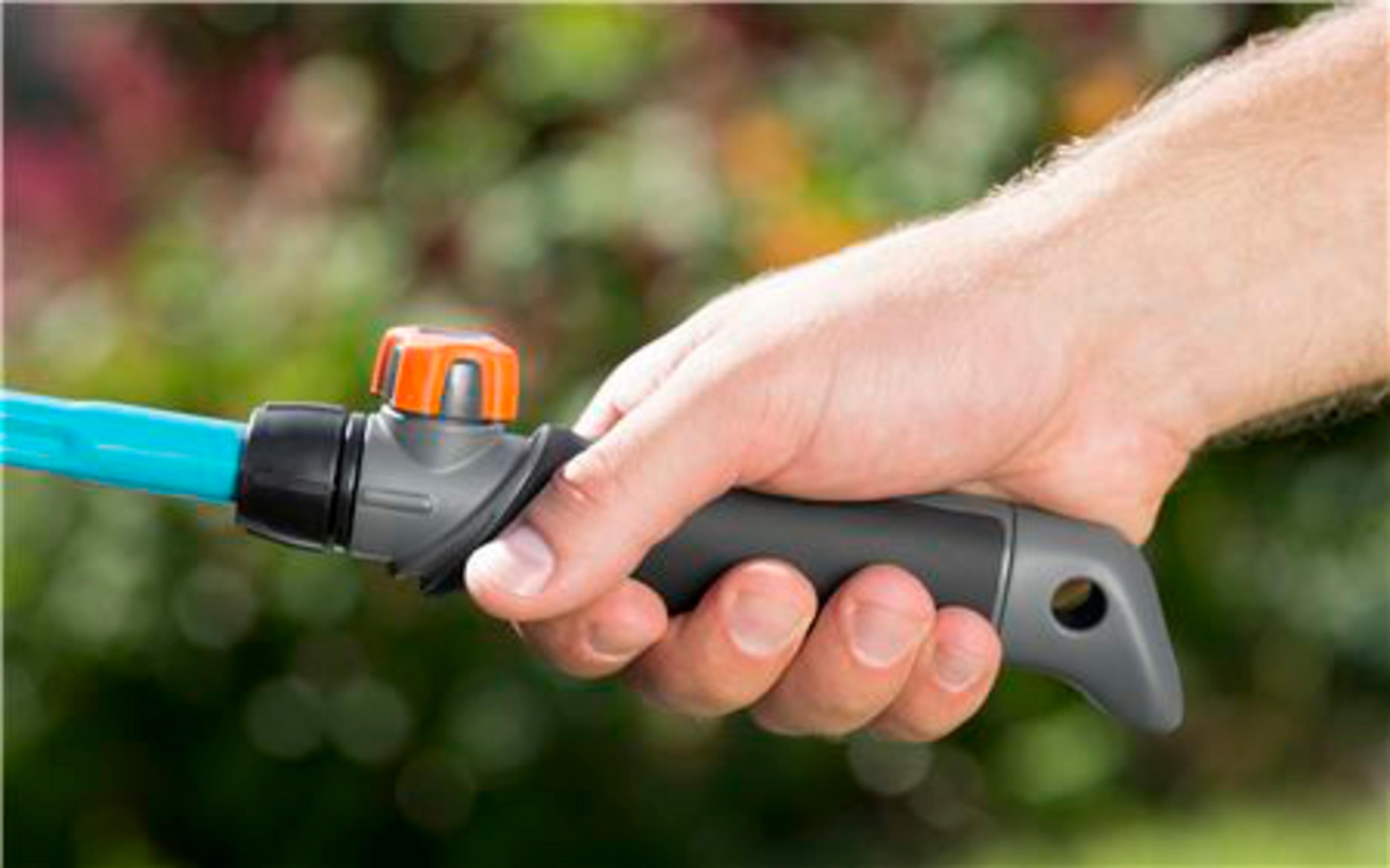 Eine Hand hält einen Gartenschlauchgriff mit blauem Schlauch und orangefarbenem Ventil.