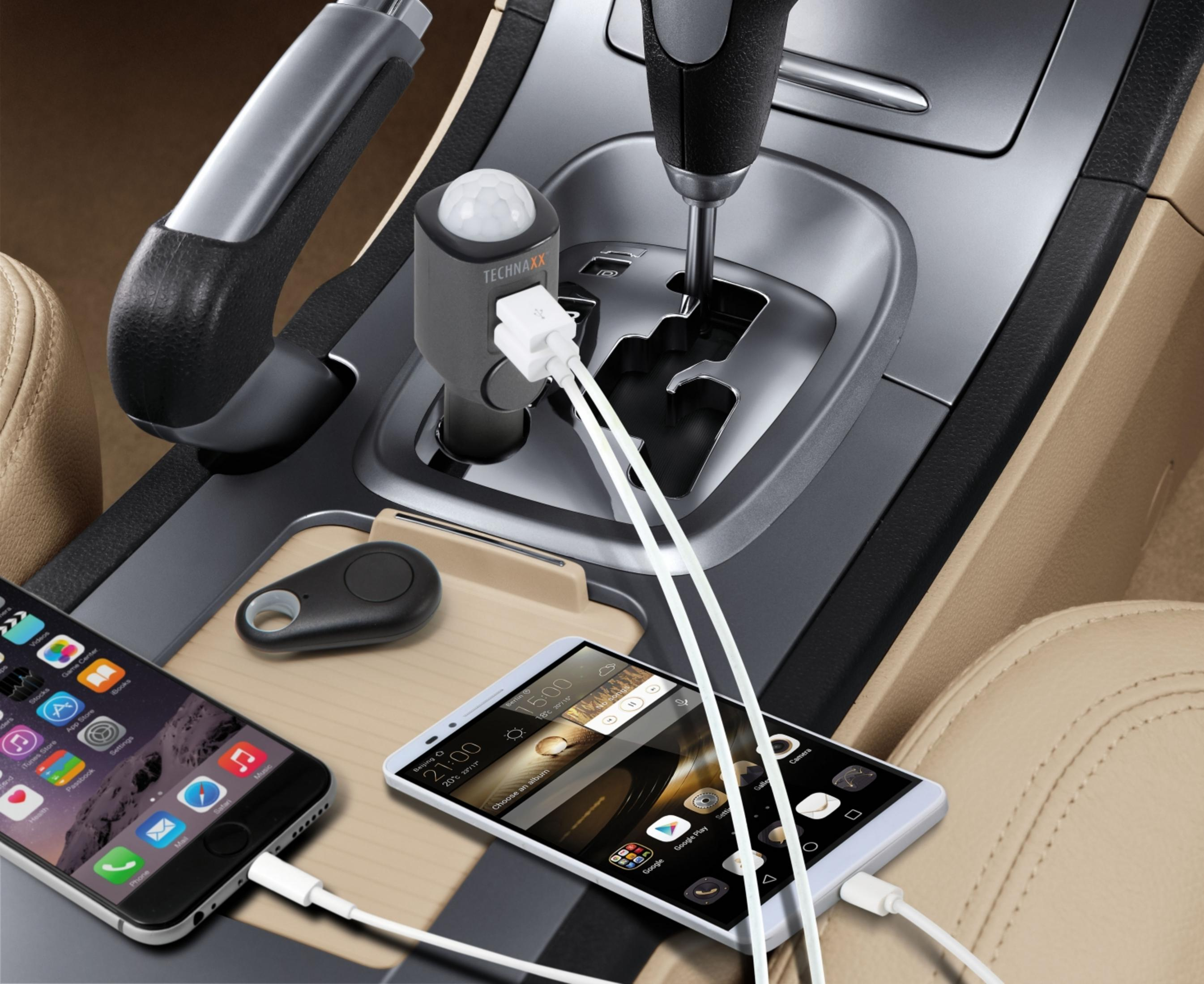 Zwei Smartphones und ein Schlüsselanhänger werden im Auto geladen.