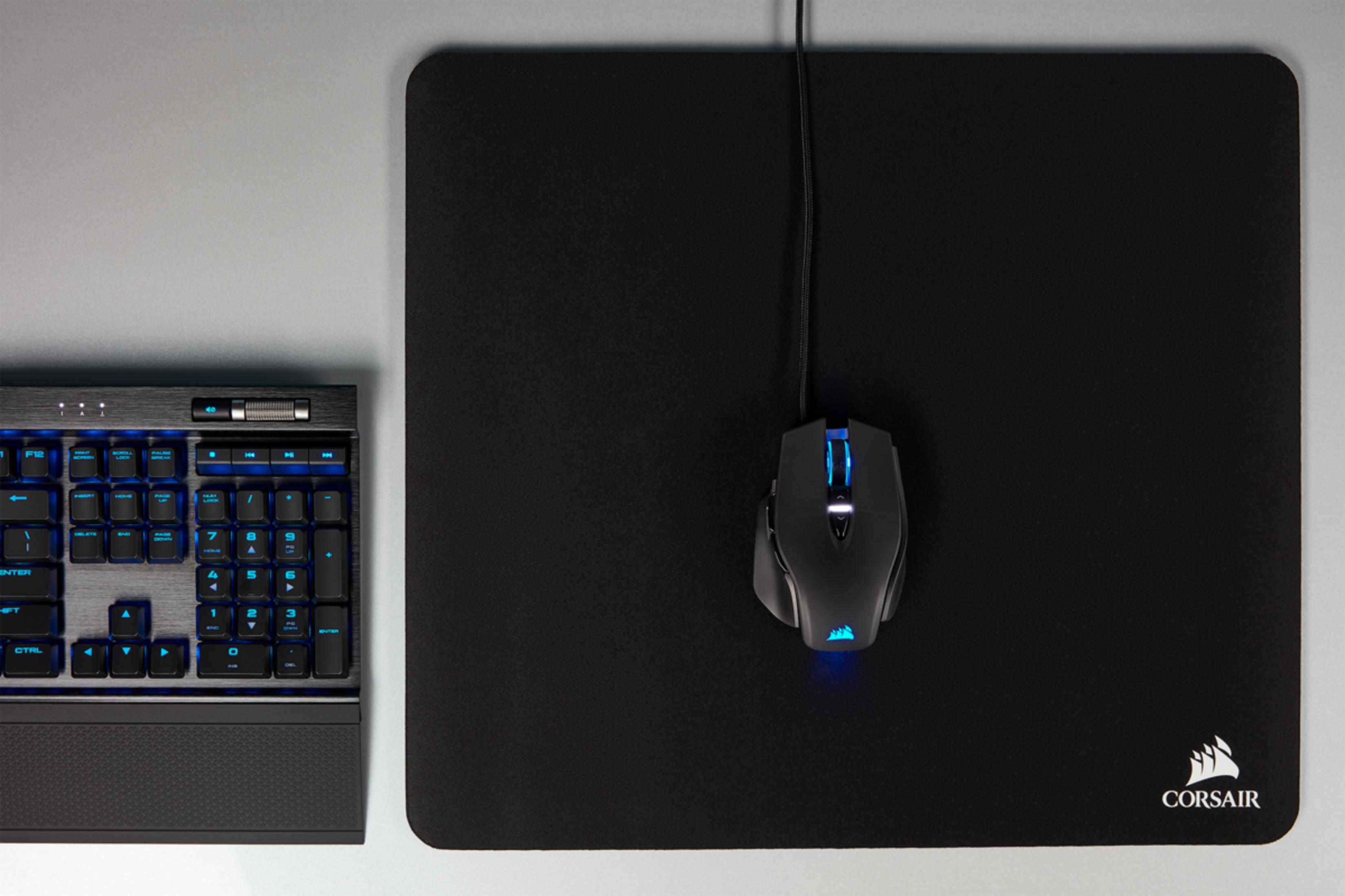 Czarna klawiatura z niebieskimi klawiszami i czarna mysz na czarnej macie.