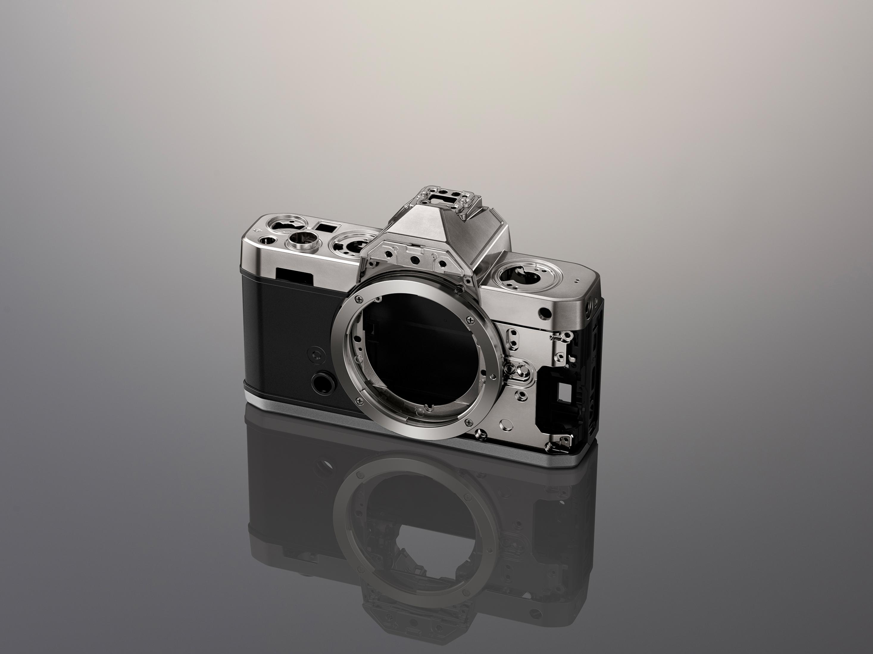 Een zilveren camerabody zonder lens, zwarte grip en reflectie.