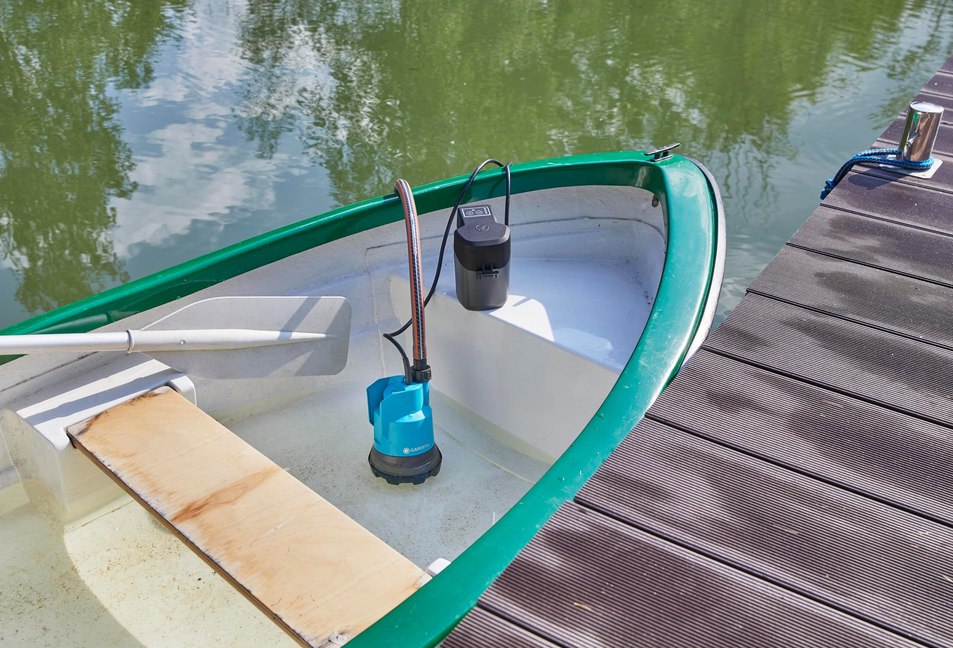 Un ensemble de pompe submersible bleu-noir avec tuyau dans un petit bateau.