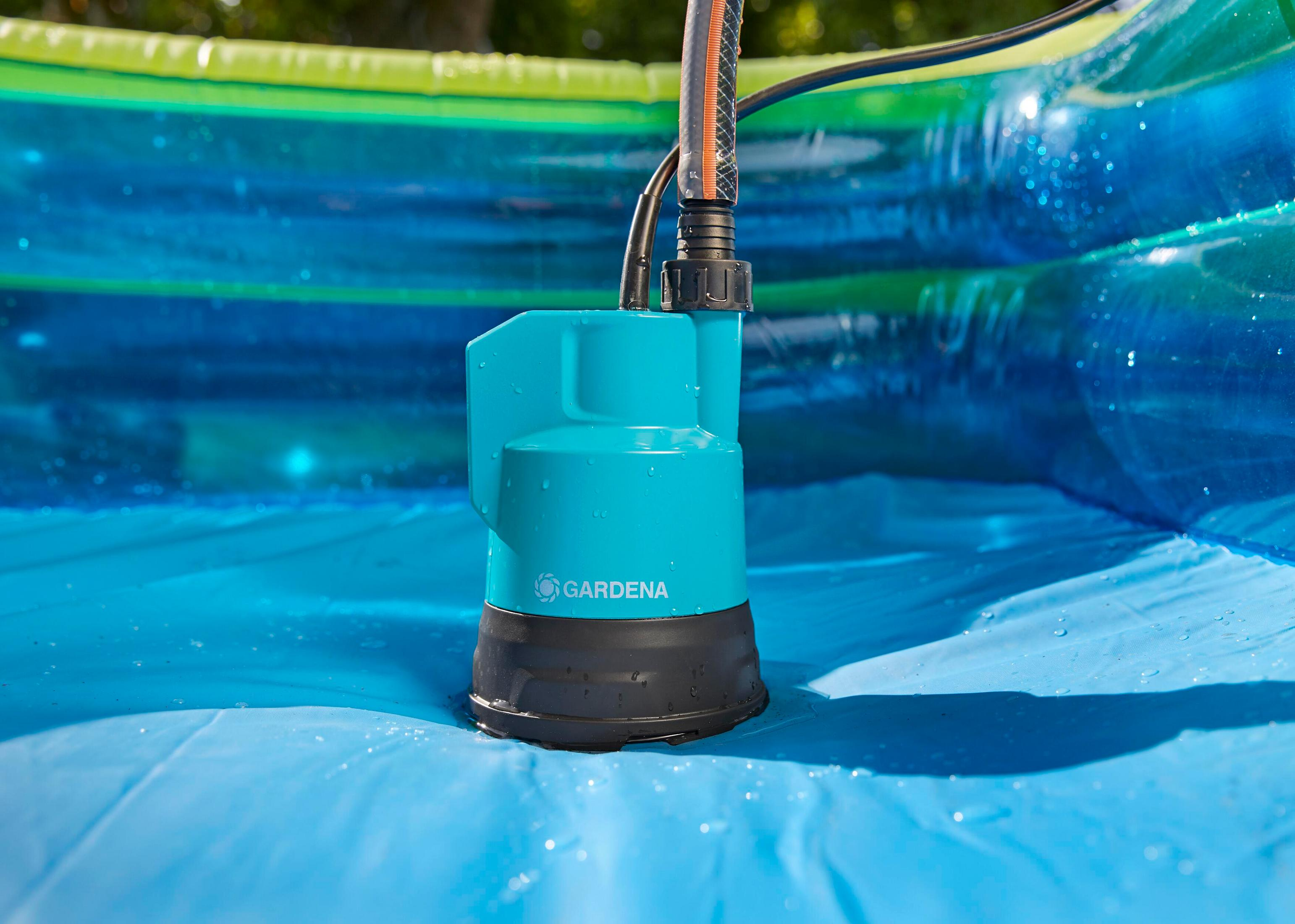 Une pompe GARDENA bleue avec tuyau dans une piscine gonflable aux anneaux bleu-vert.