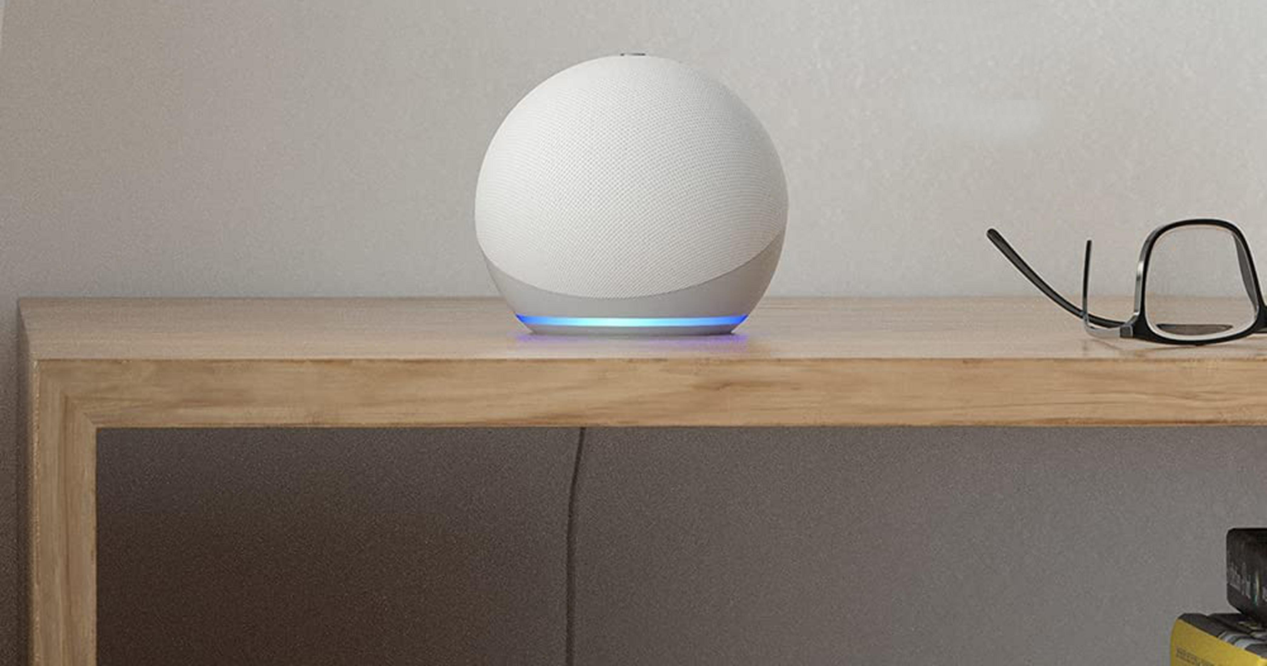 Ein weißer, kugelförmiger Smart Speaker mit blauer Beleuchtung auf einem Holztisch.